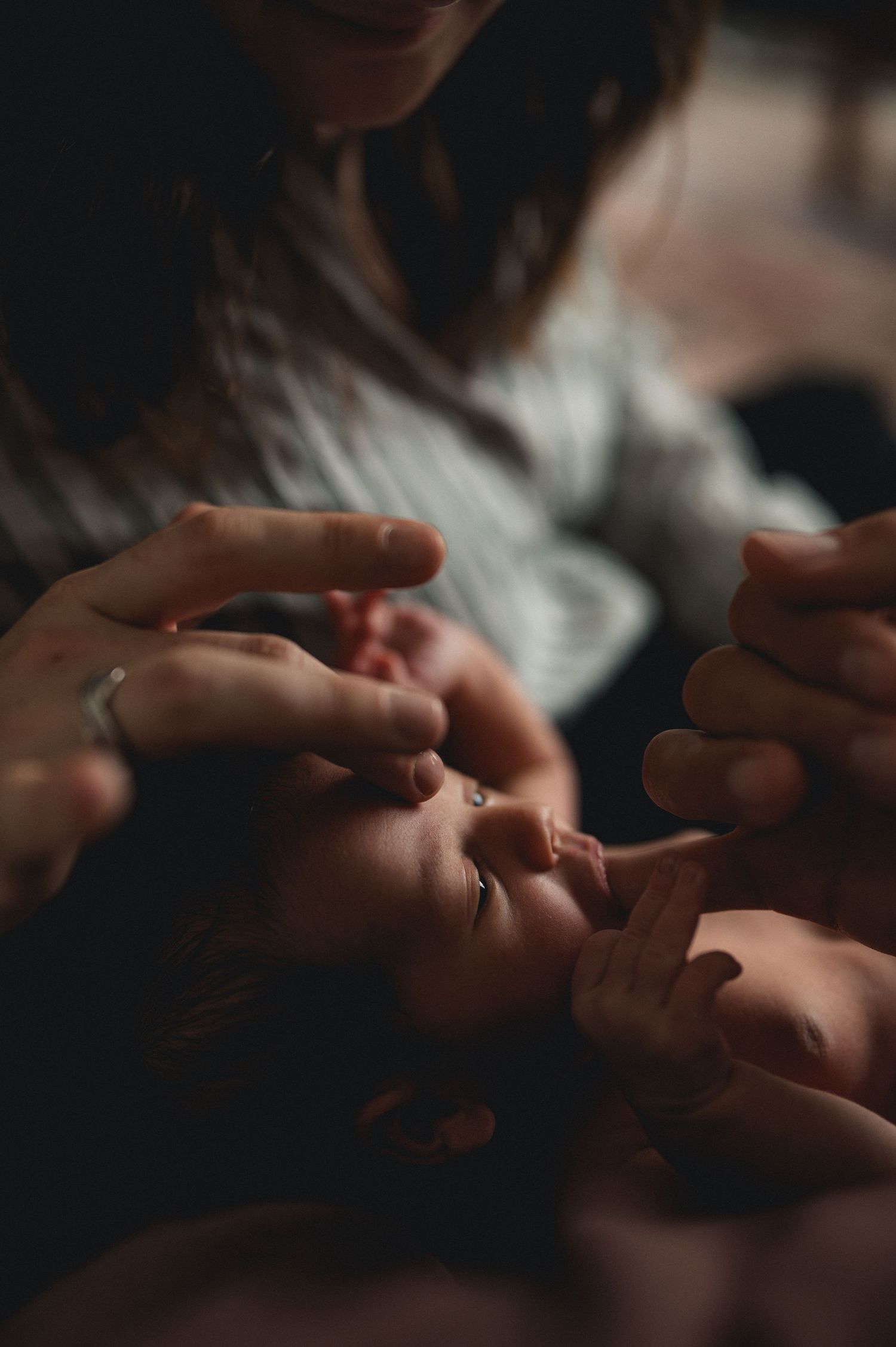 Mother tenderly touching her sleeping newborn baby's face with gentle hands.