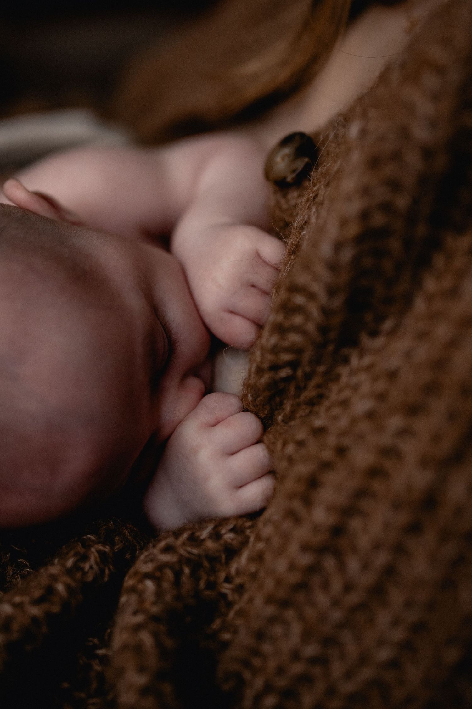 Close-up of sleeping newborn baby wrapped in a brown knit blanket.