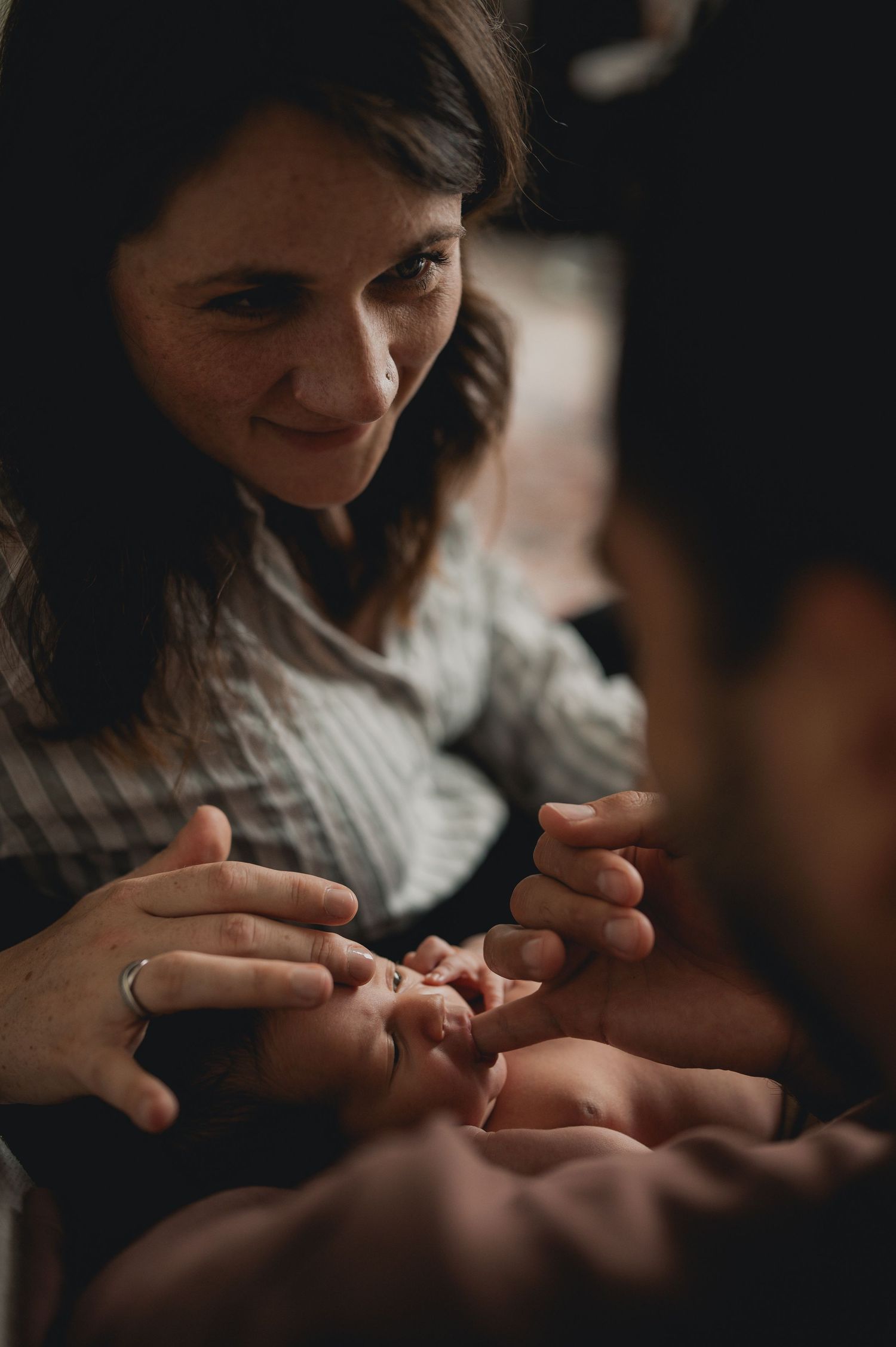 Smiling mother tenderly touching her newborn babys tiny fingers.