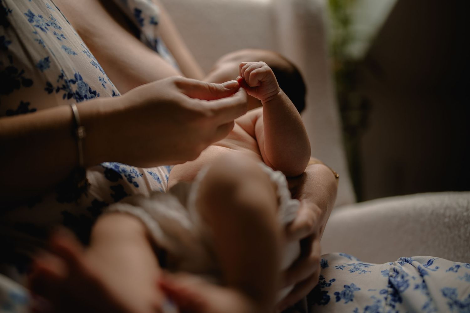 Close-up of a mother gently holding her newborn baby's tiny hand in a tender moment.