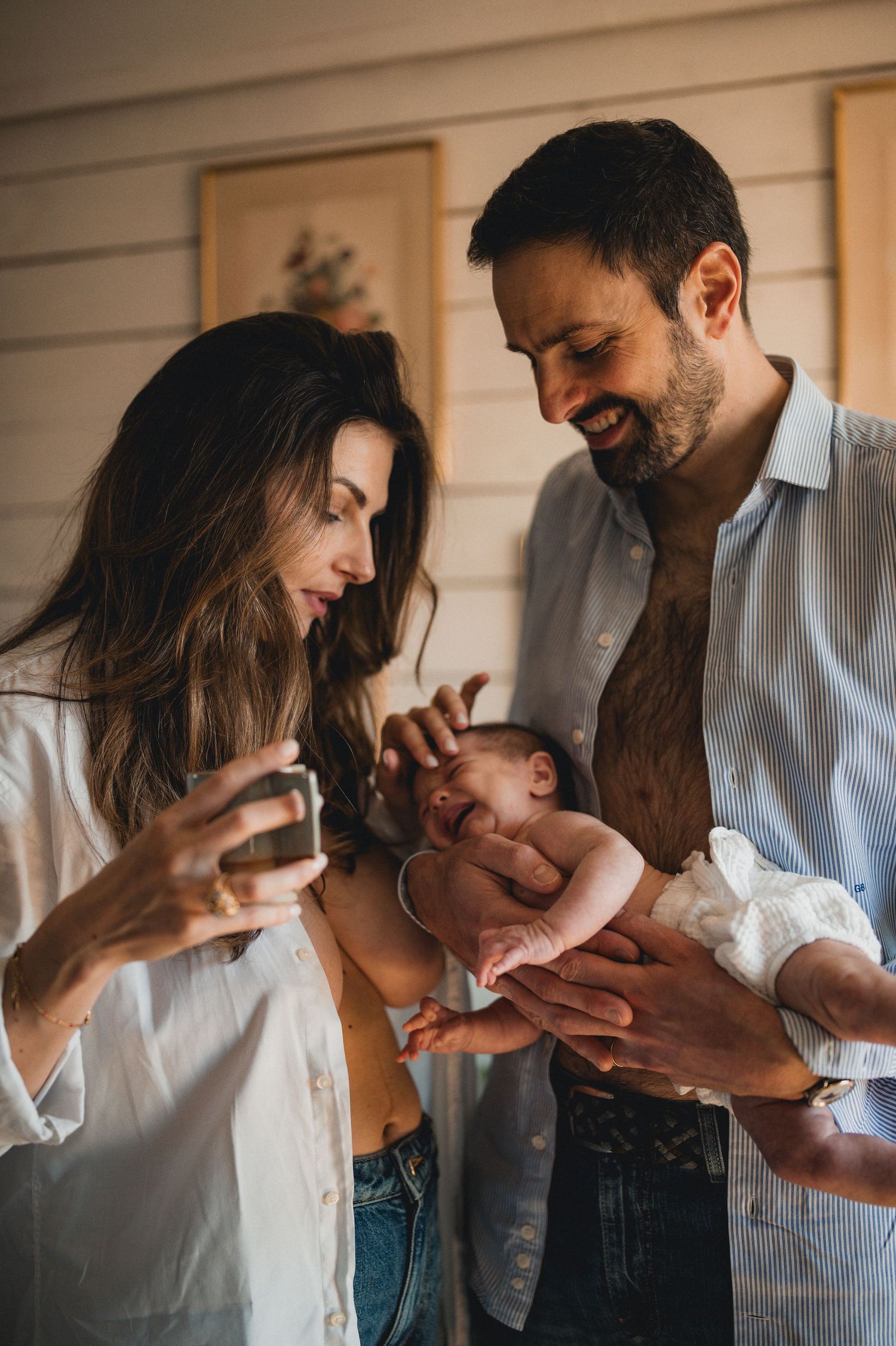 Smiling parents admiring their sleeping newborn baby held by the father.