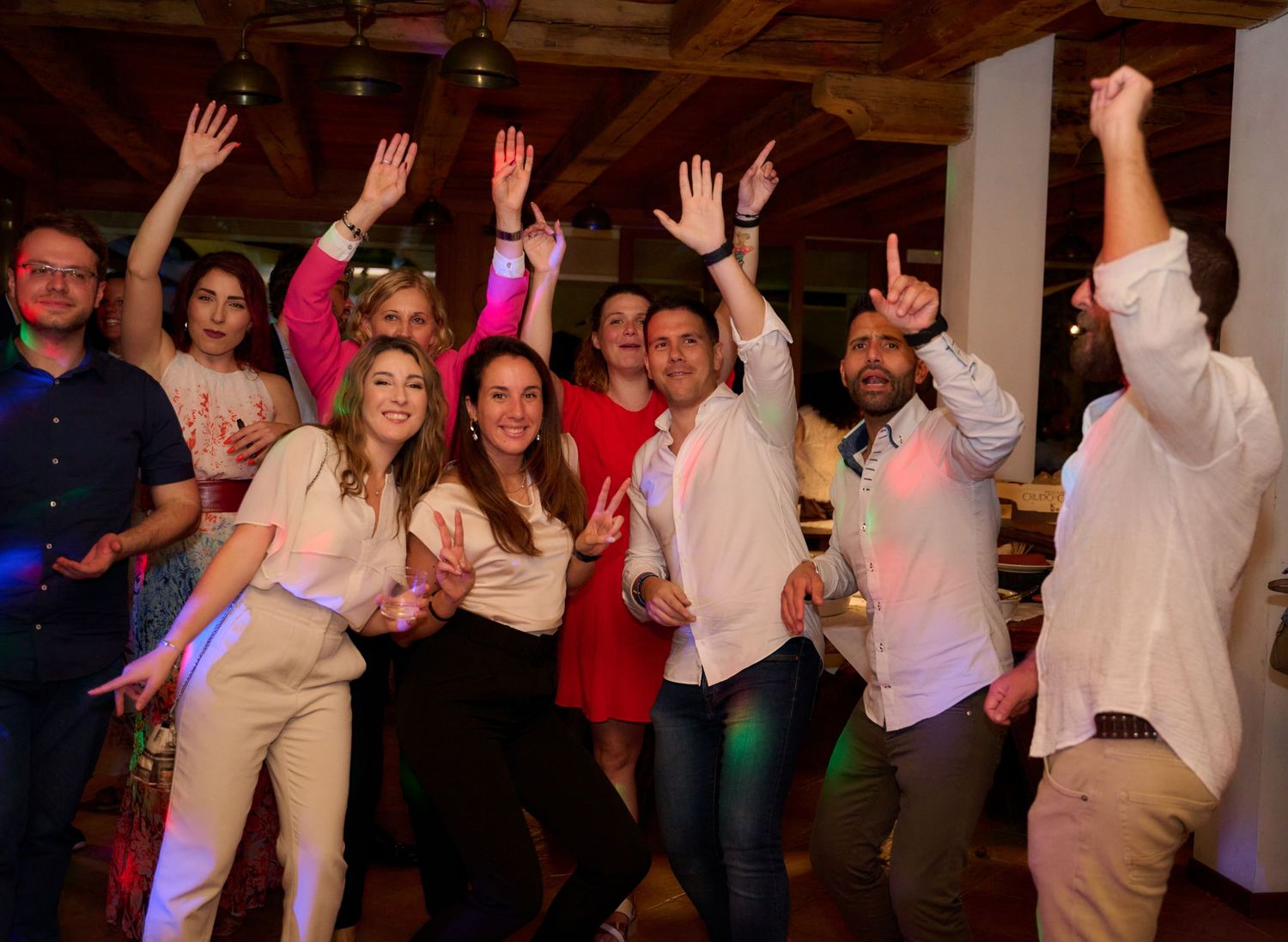 Group of friends dancing and celebrating with raised hands at a party.