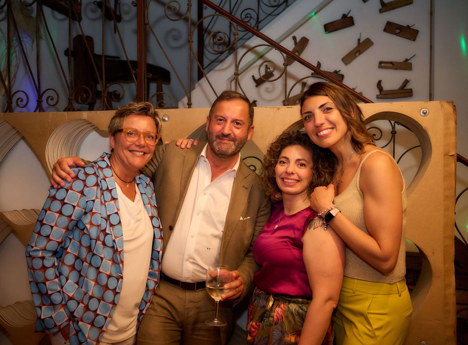 Four friends pose together smiling at a festive evening party celebration.