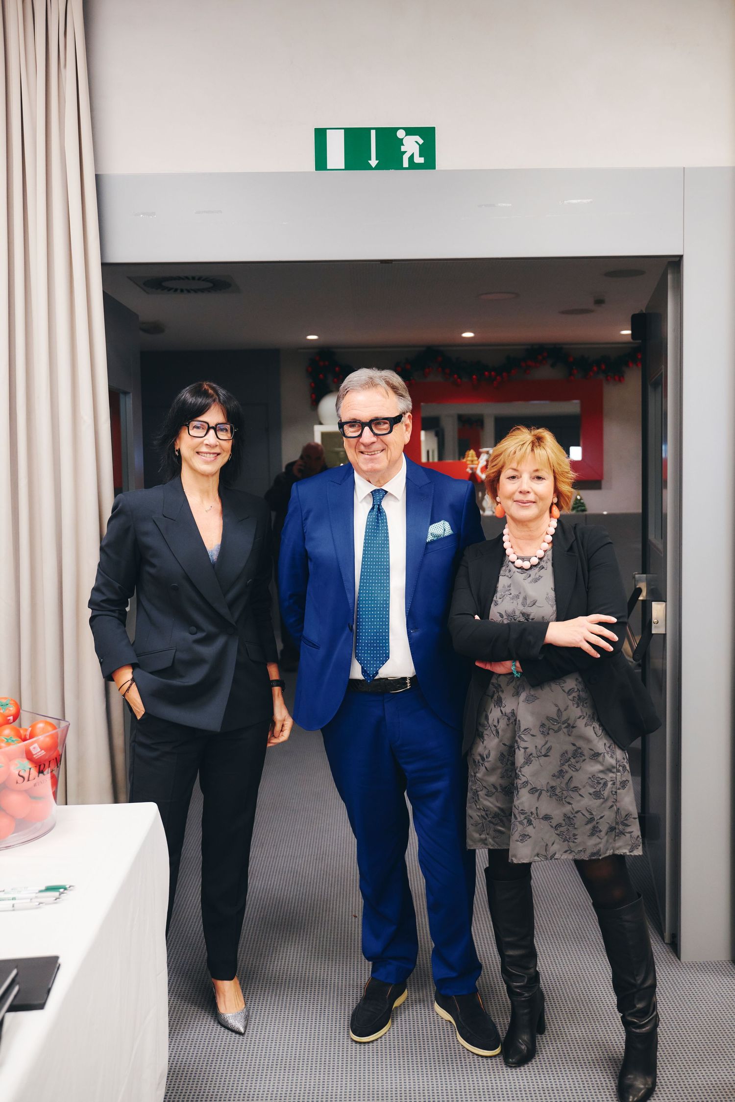 Three professionals posing together at a corporate event in a modern conference room.