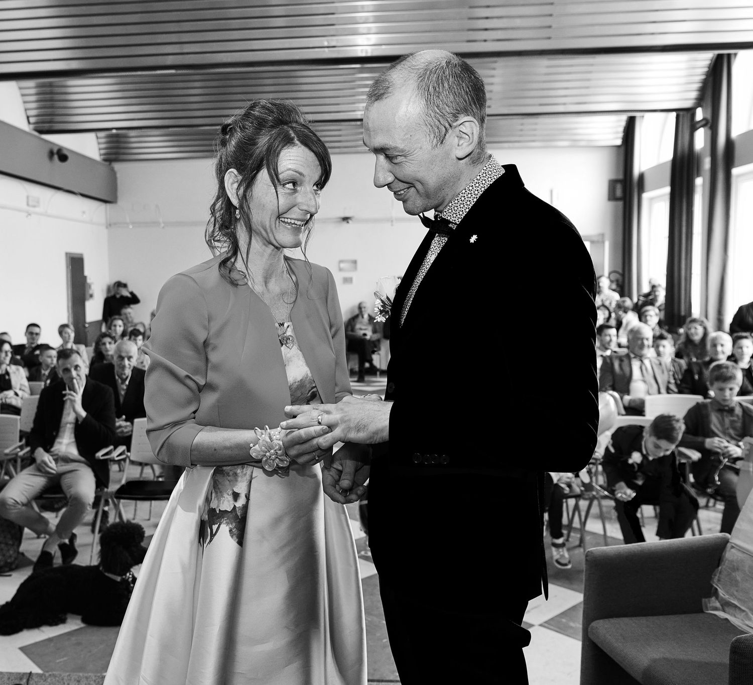 Black and white photo of a couple exchanging vows during an indoor wedding ceremony.