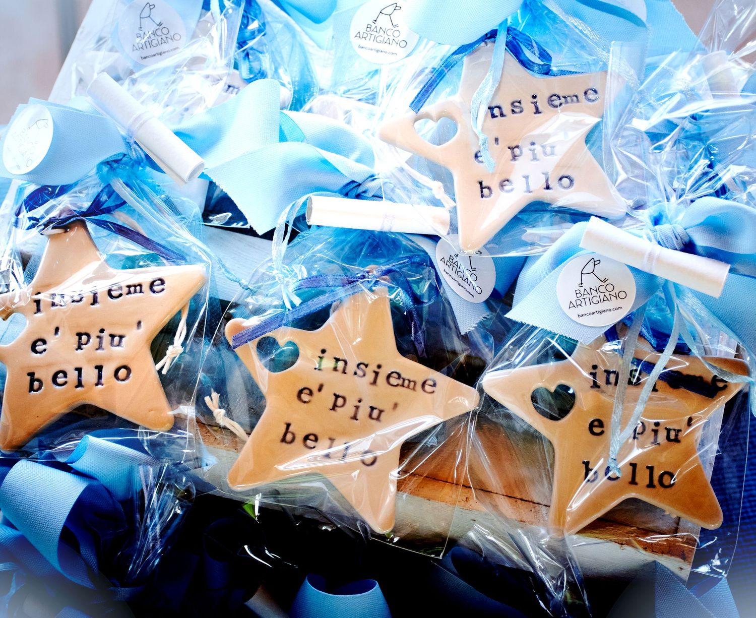 Star-shaped Italian baptism favor cookies reading insieme e piu bello wrapped in blue cellophane bags.