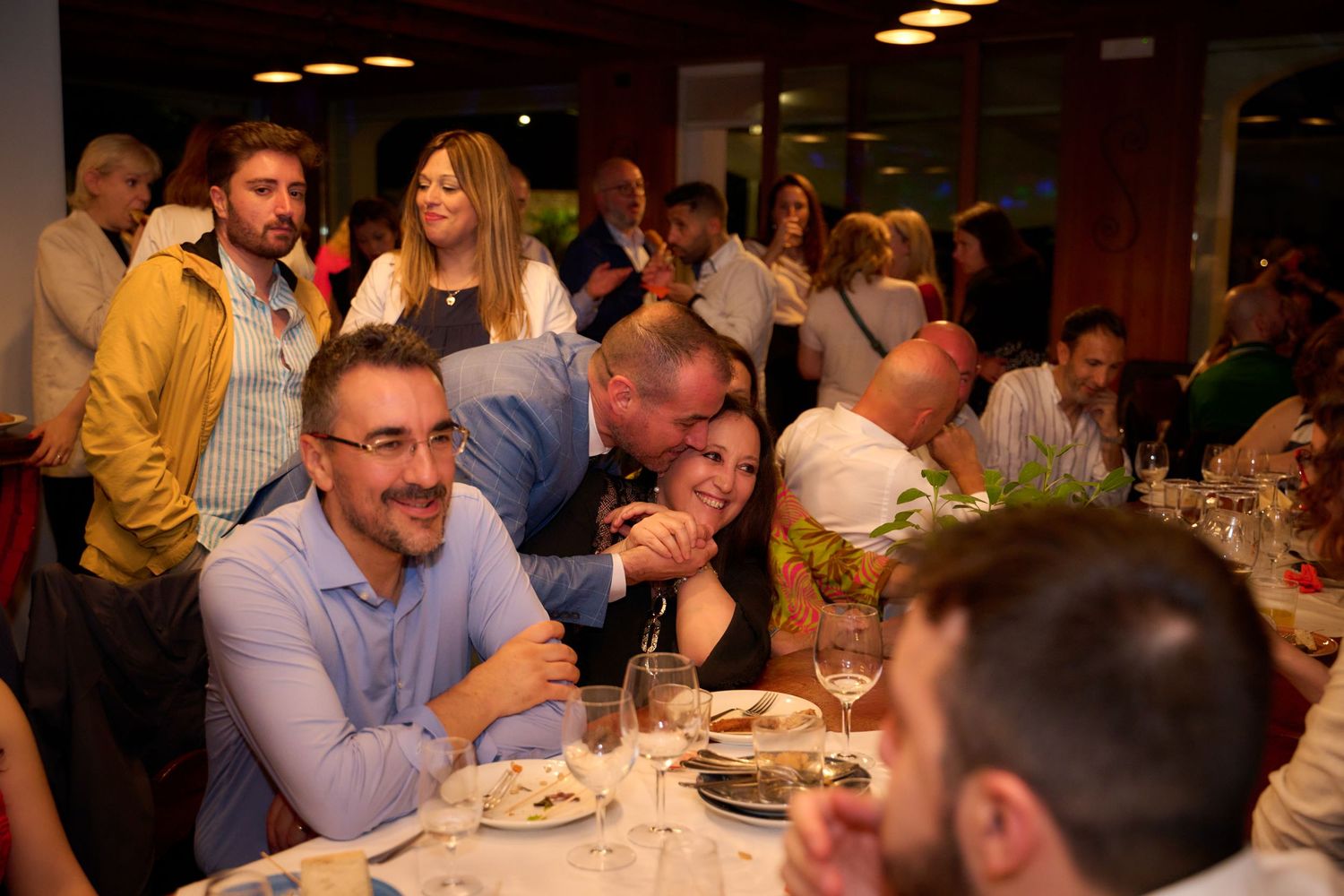 People laughing and dining together at a lively indoor social gathering event.