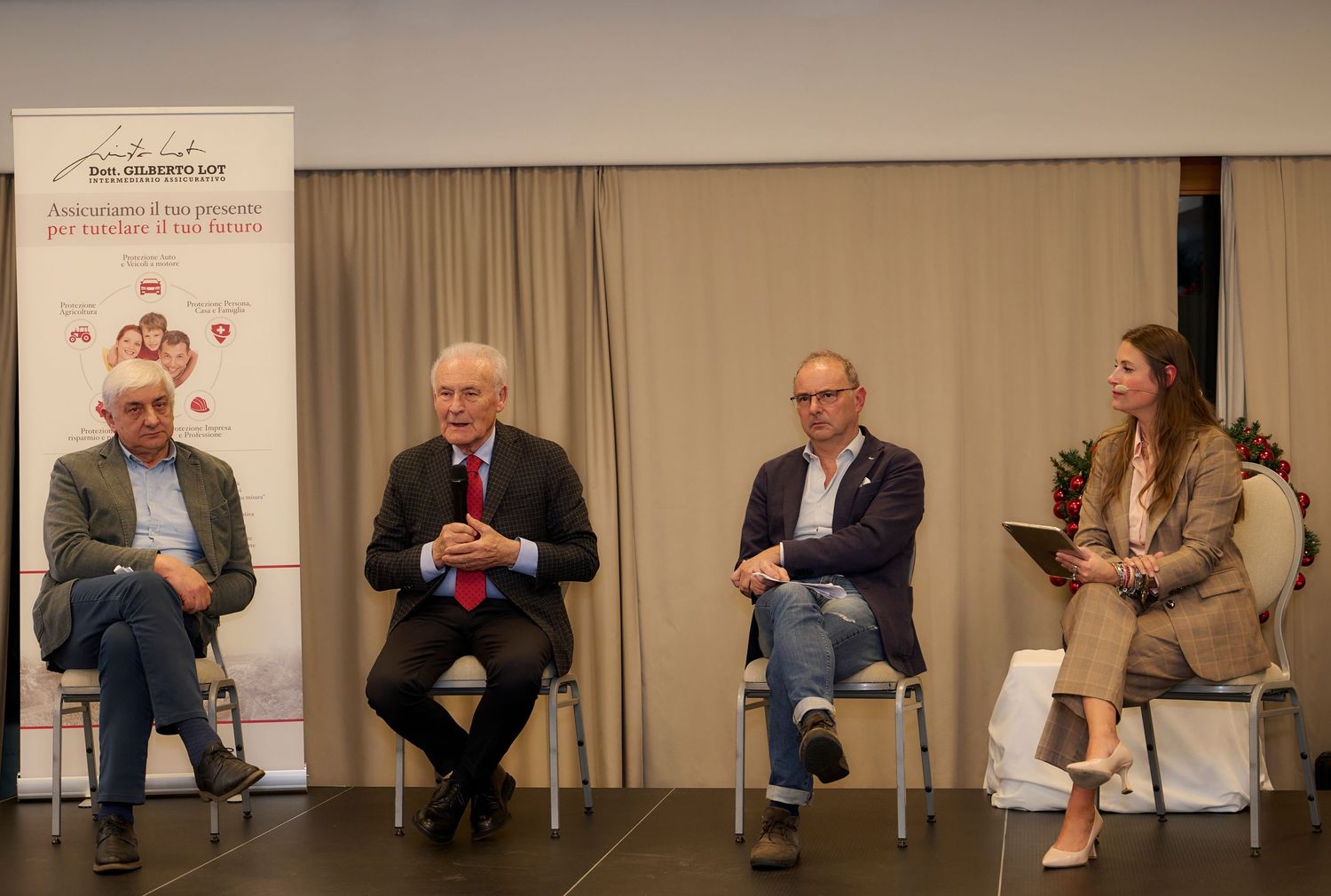 Four panelists seated on stage during a professional conference discussion.