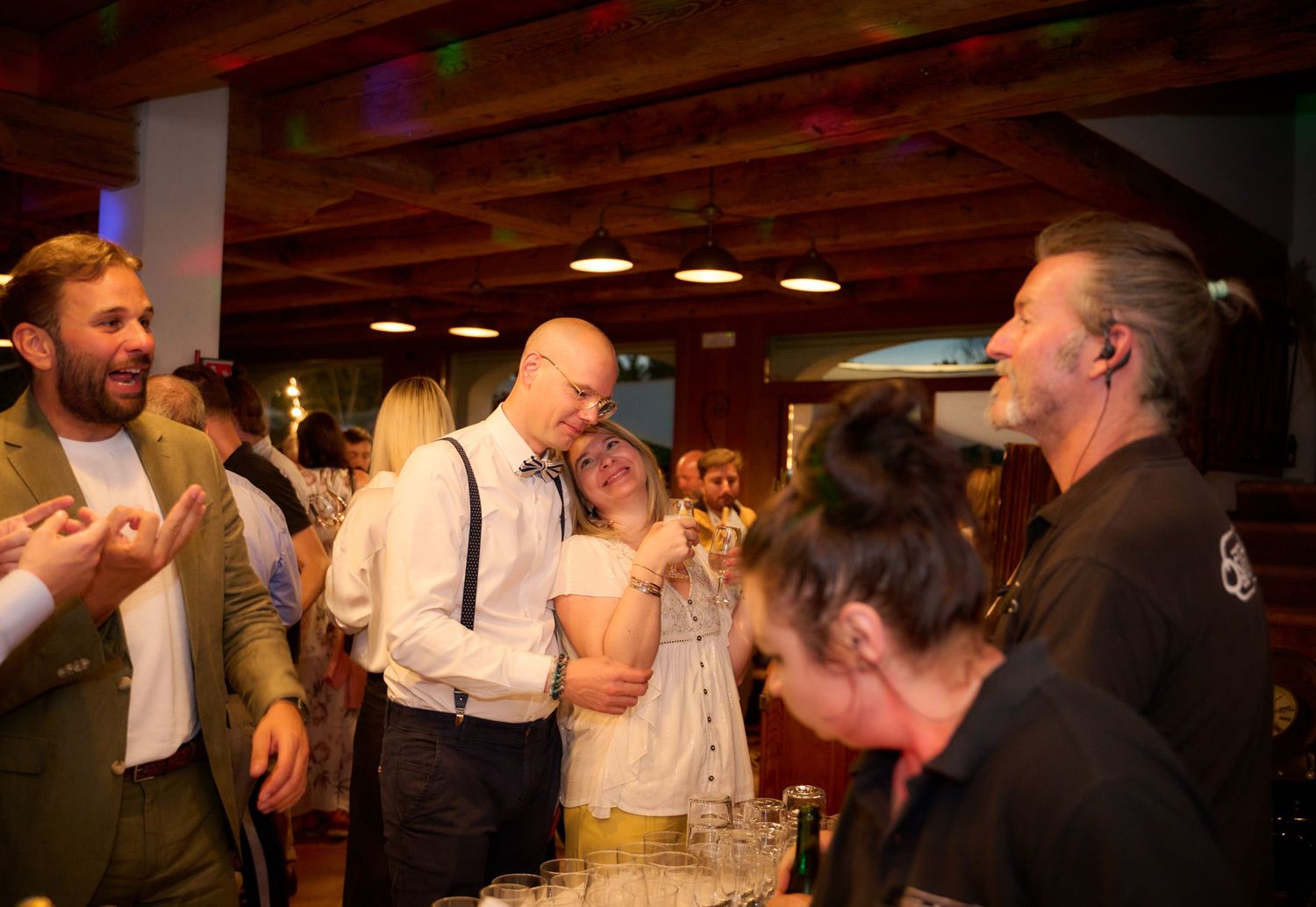Group of people socializing and laughing together at an indoor party or reception event.