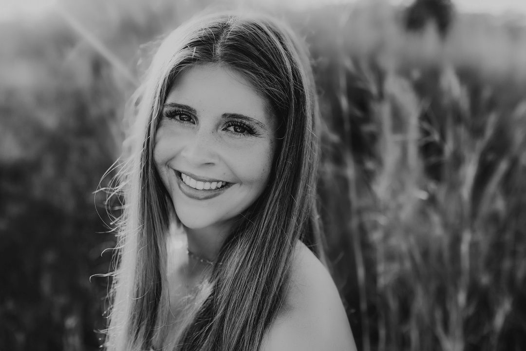 Black and white portrait of smiling young woman in field.