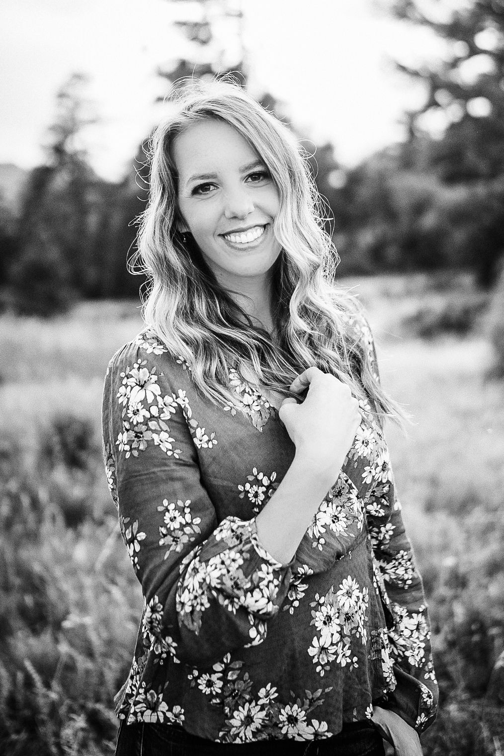 Beautiful blonde woman smiles in black and white portrait outdoors in field.