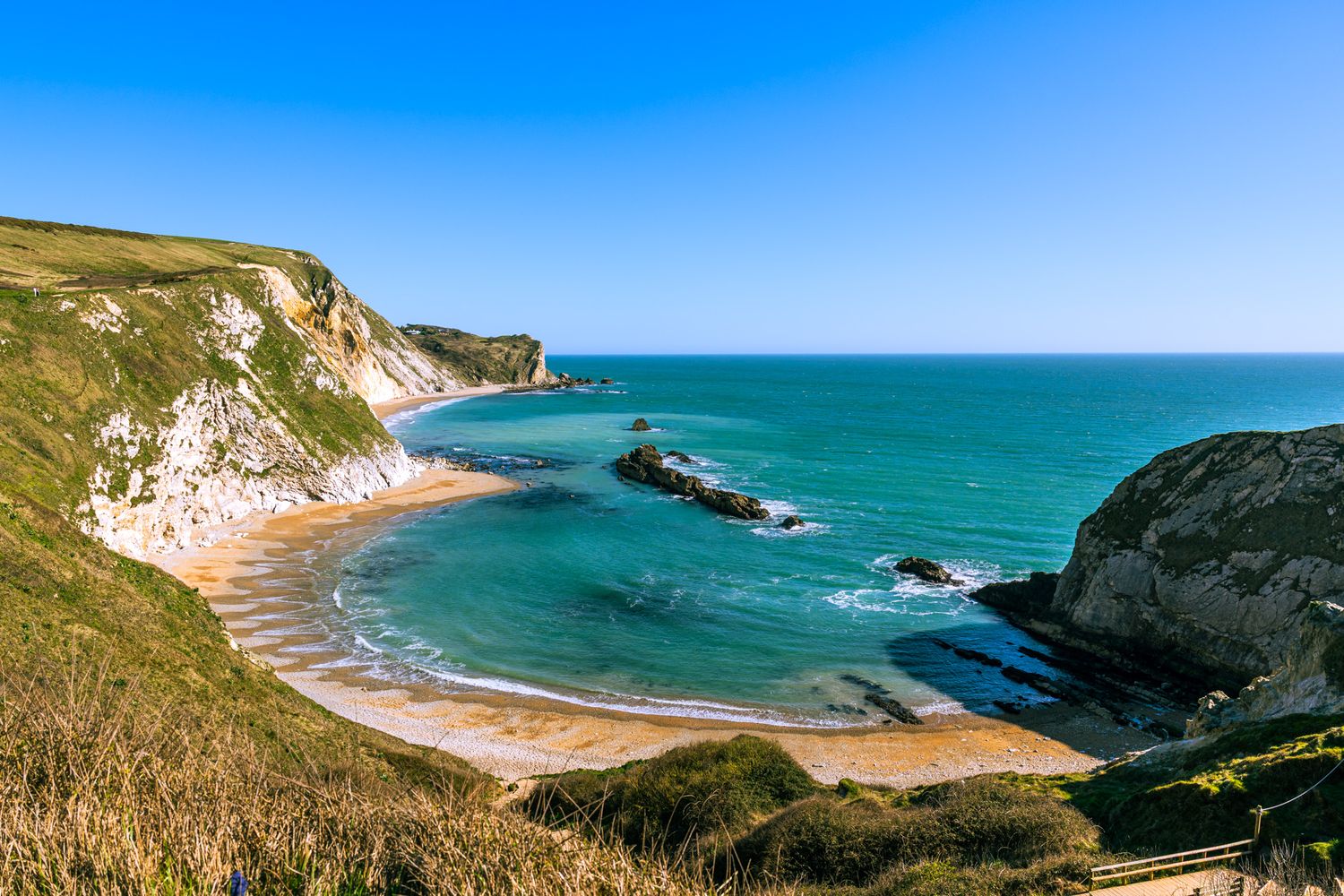 Stunning aerial view of Man O'War Cove in Dorset with turquoise waters, white chalk cliffs, and rocky outcrops.