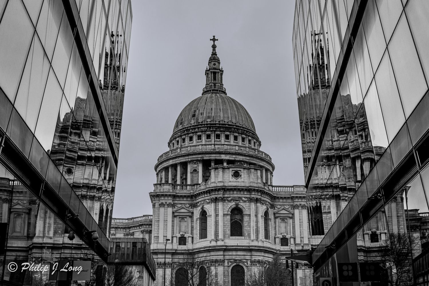 Black and white photo of St Pauls Cathedral framed between two modern glass buildings.