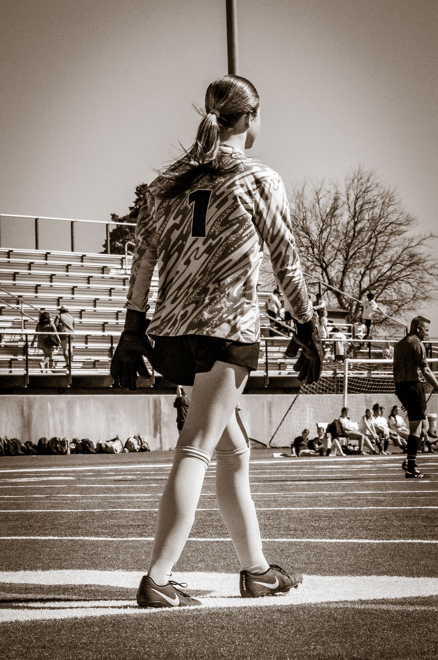 Black and white photo of person walking outdoors on pavement