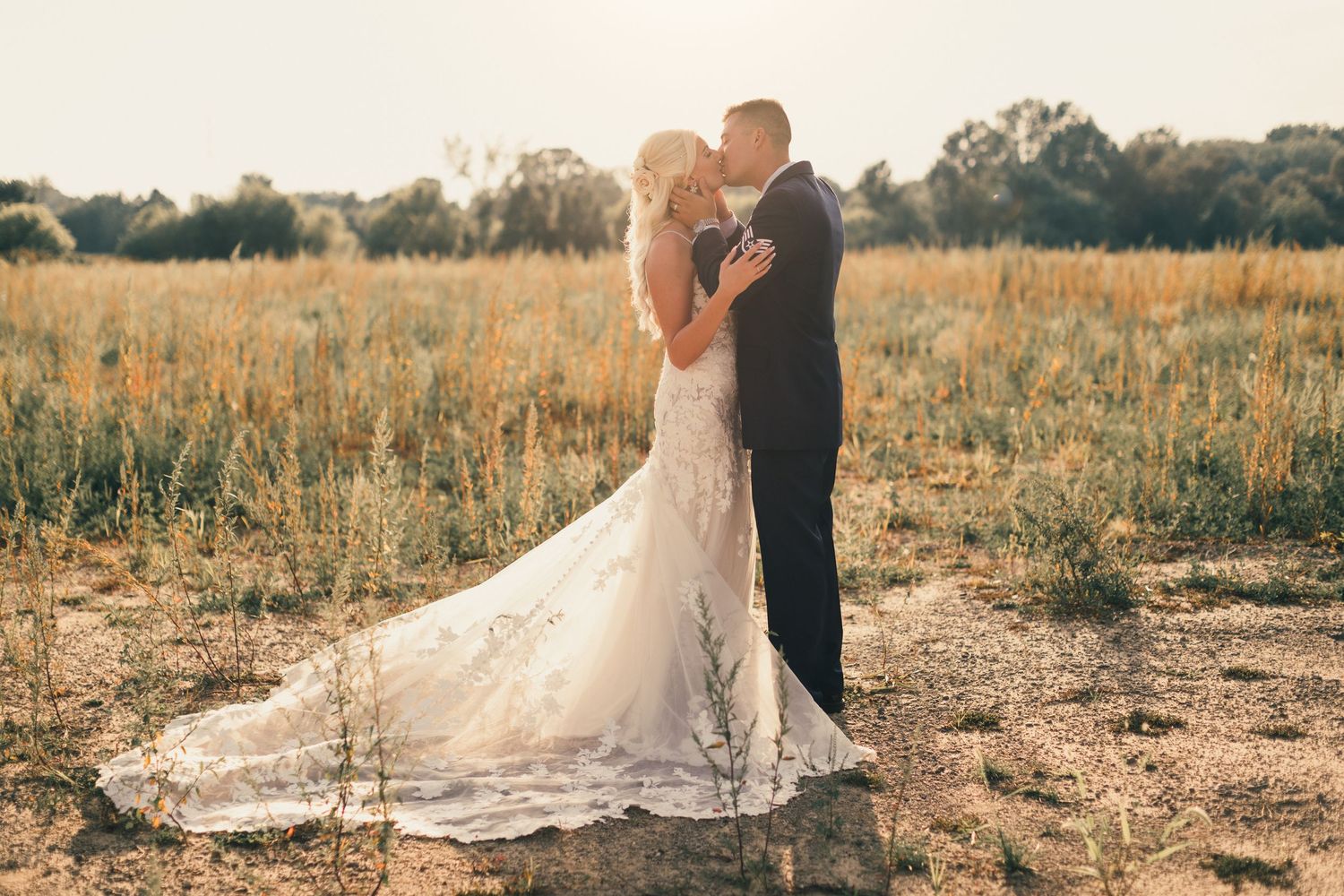 Wedding couple poses together in a golden field during sunset for romantic portraits.