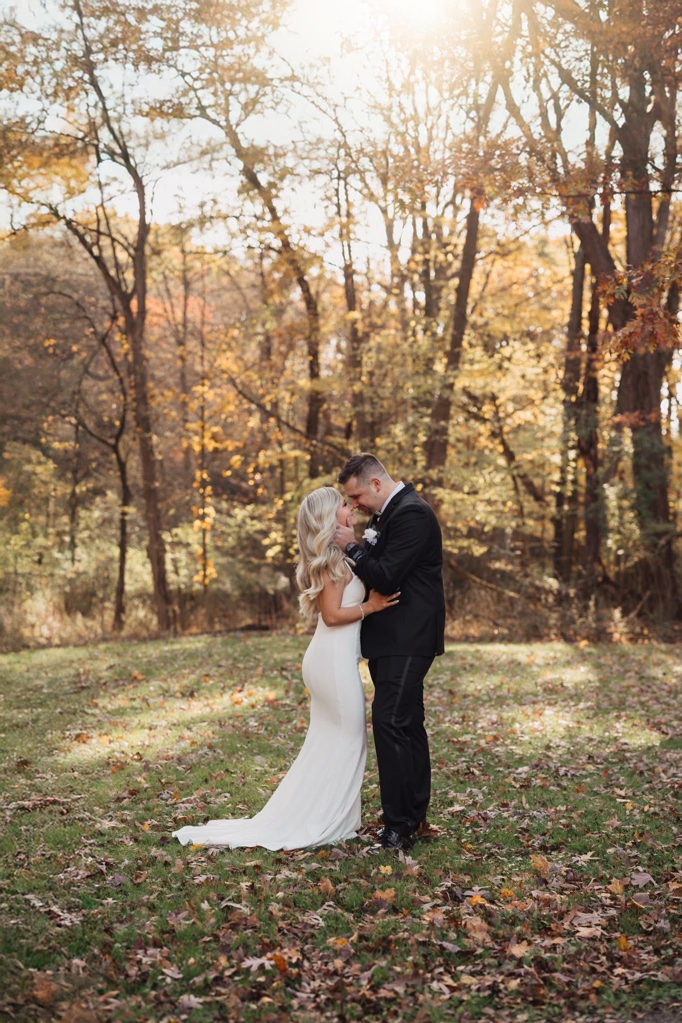 Autumn wedding portraits with fallen leaves and golden sunlight filtering through trees.