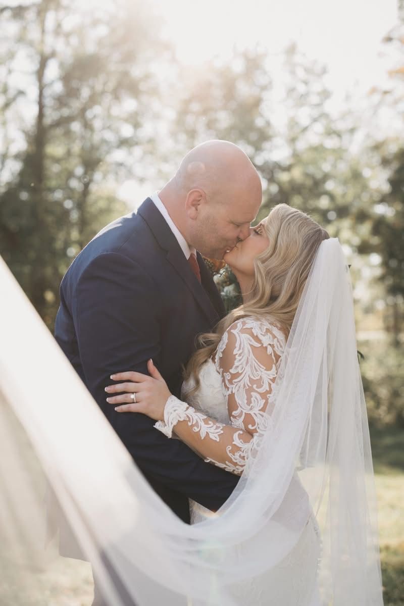 Romantic wedding couple embracing outdoors in golden sunlight.