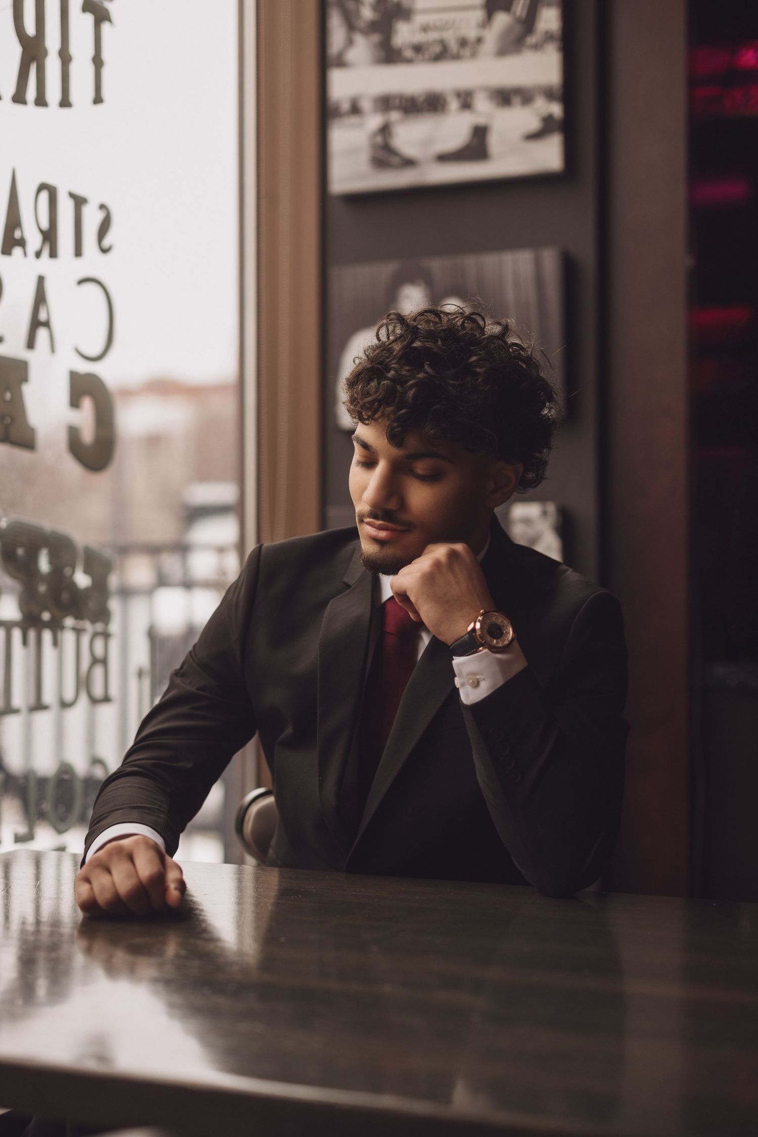 Person in suit and tie sitting contemplatively at bar counter.