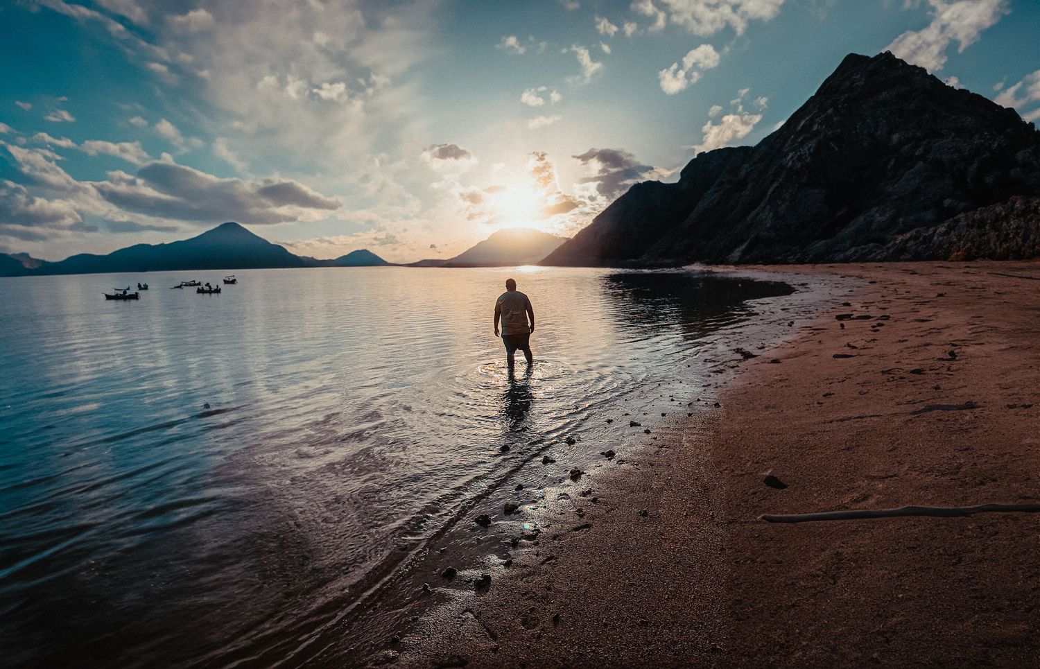 Dramatic coastal landscape series with silhouettes against sunset and mountain backdrop.