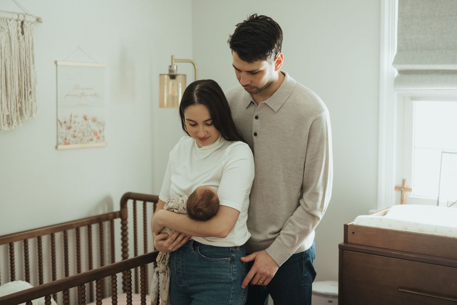 Tender moments captured in a bright nursery room with a wooden crib.