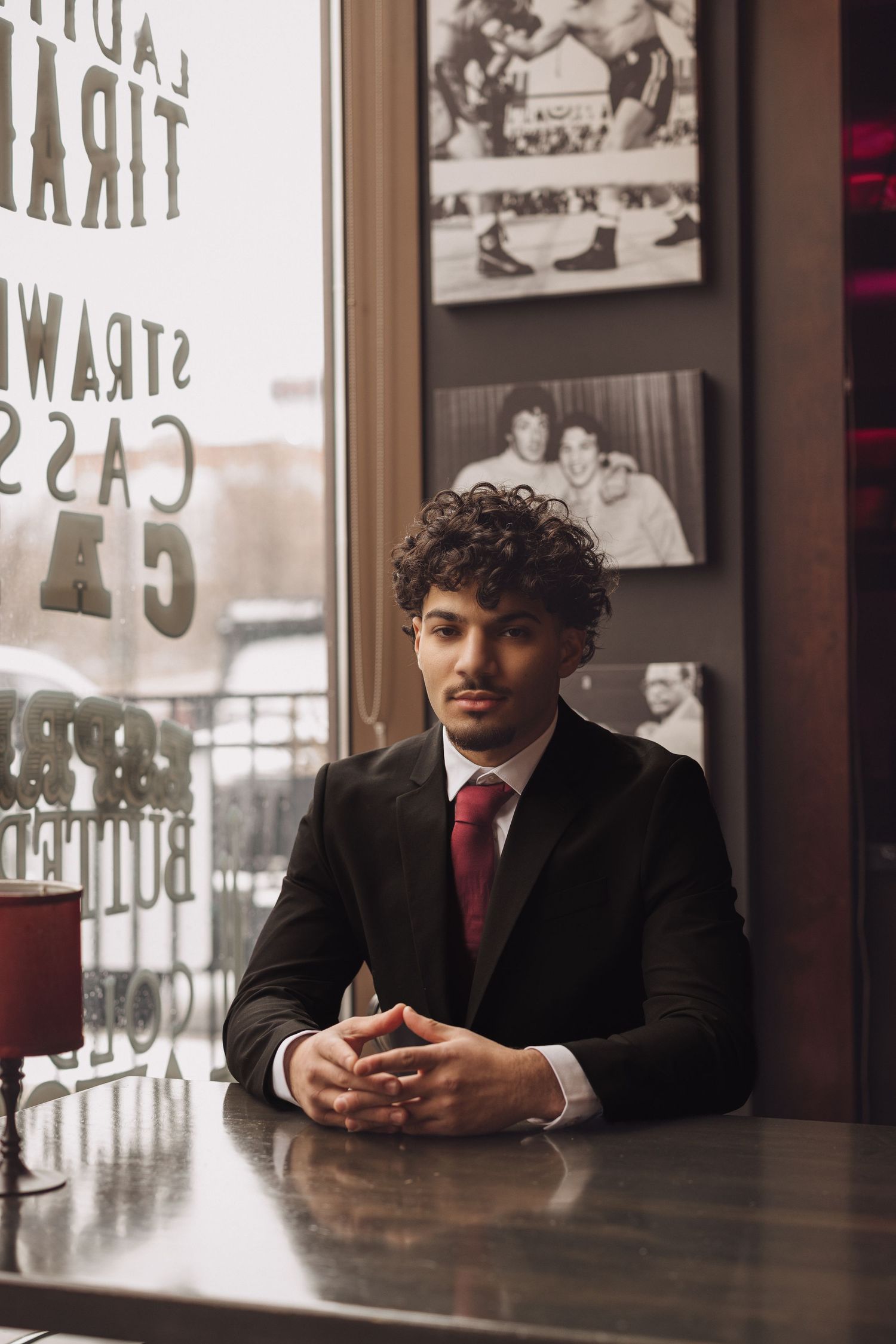 Business professional sitting at restaurant table in dark suit and red tie.