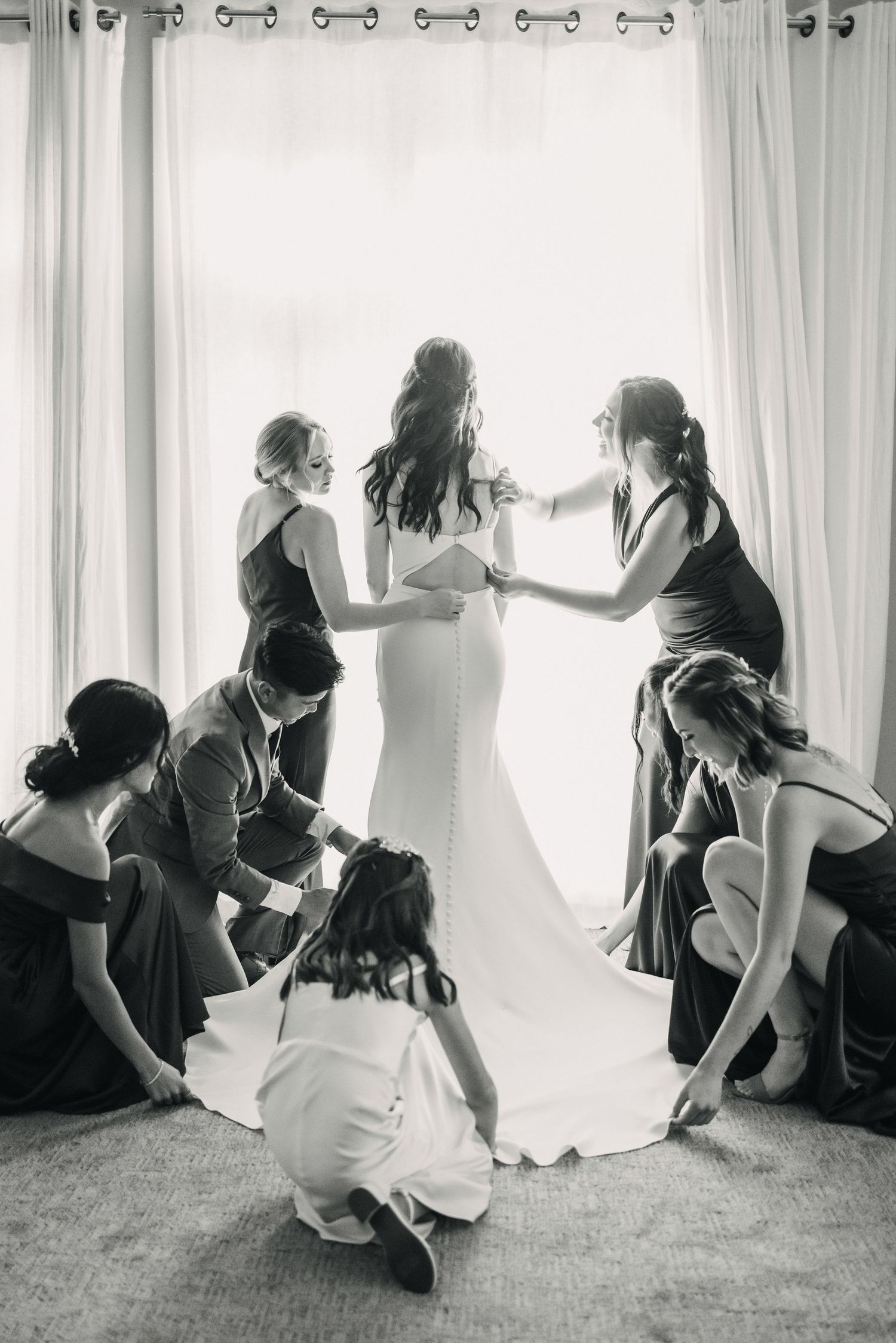 Black and white photo of bridesmaids helping with wedding preparations.