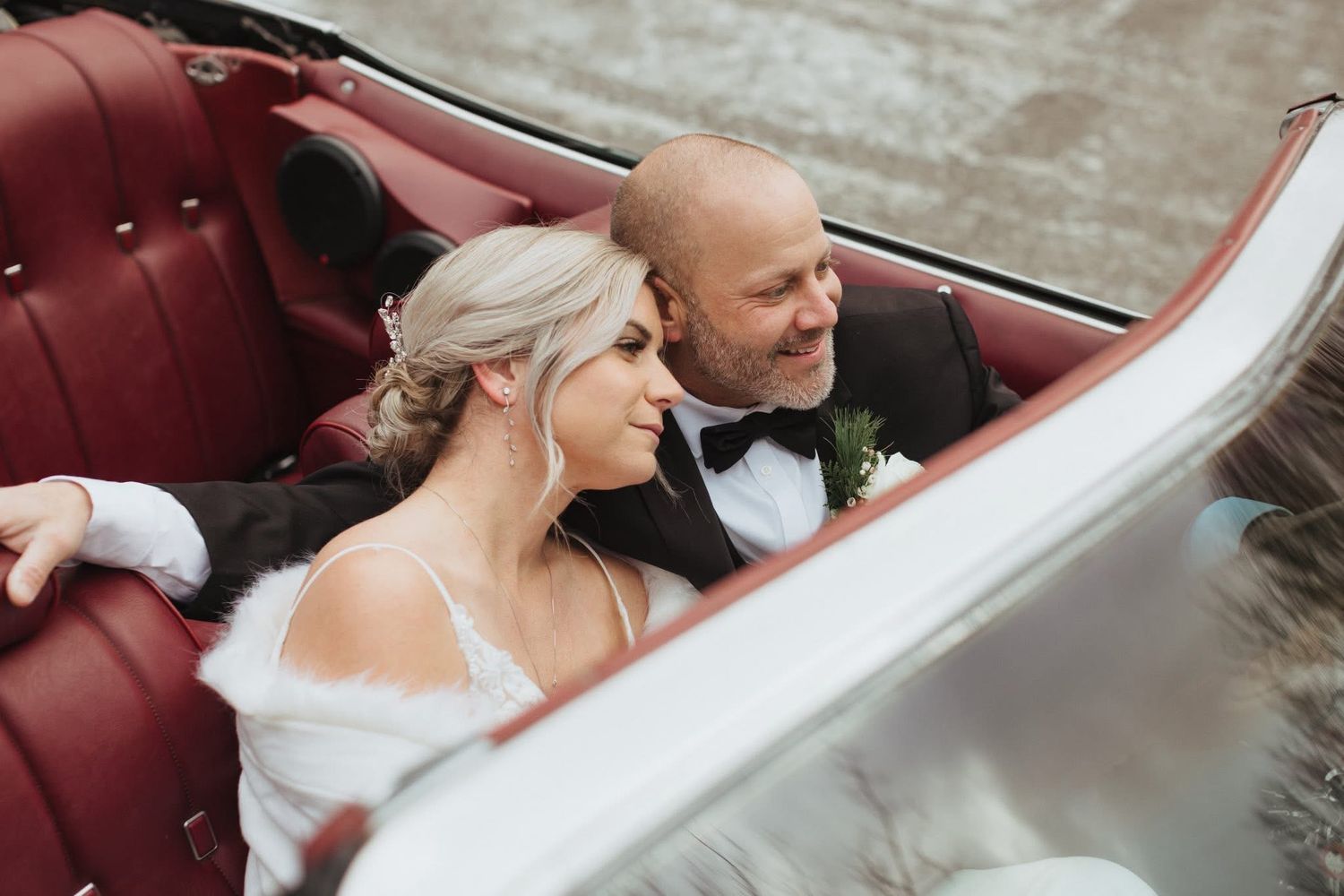 Wedding couple in vintage car with burgundy interior.
