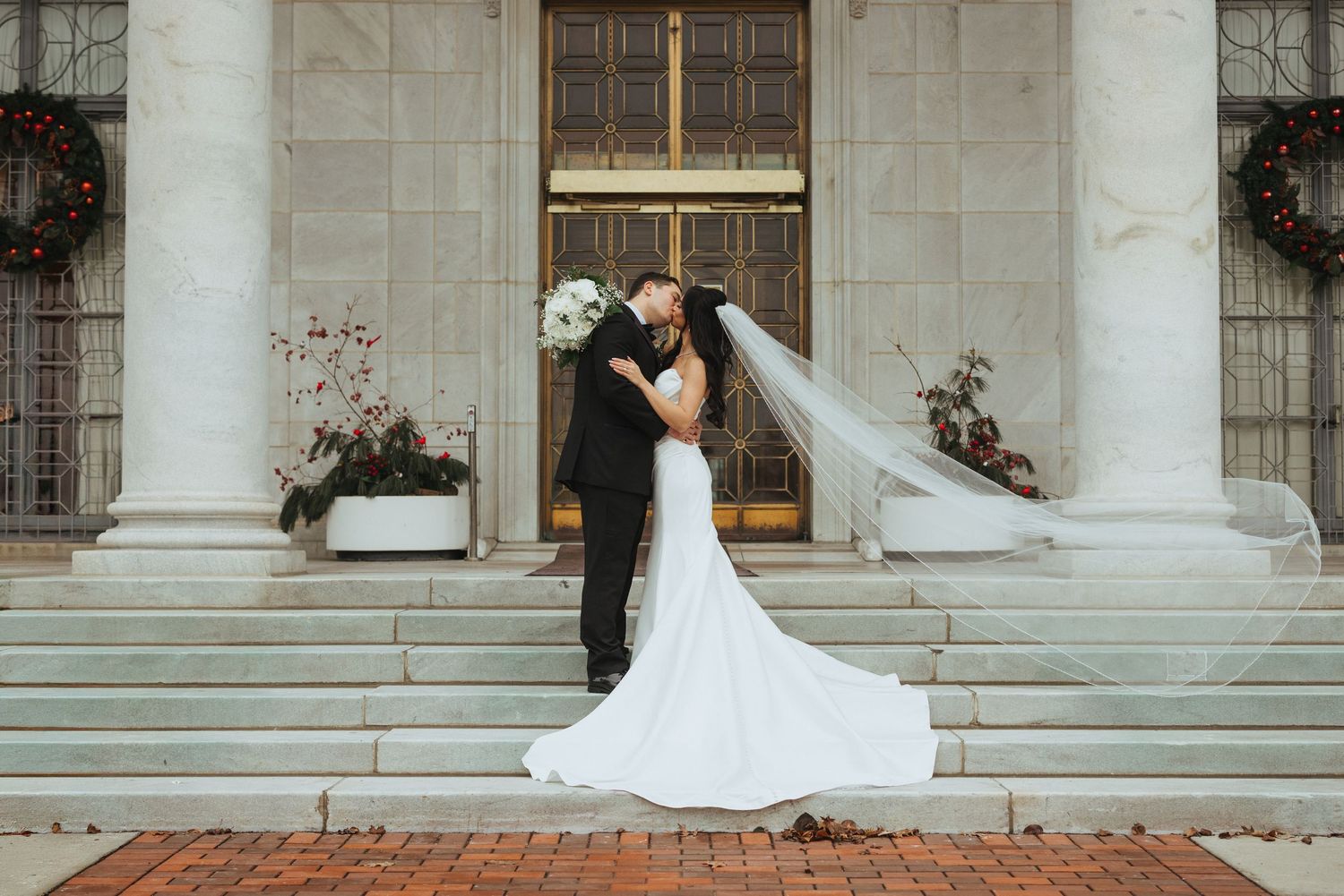 Dramatic wedding portrait on stone steps with elegant architectural backdrop.