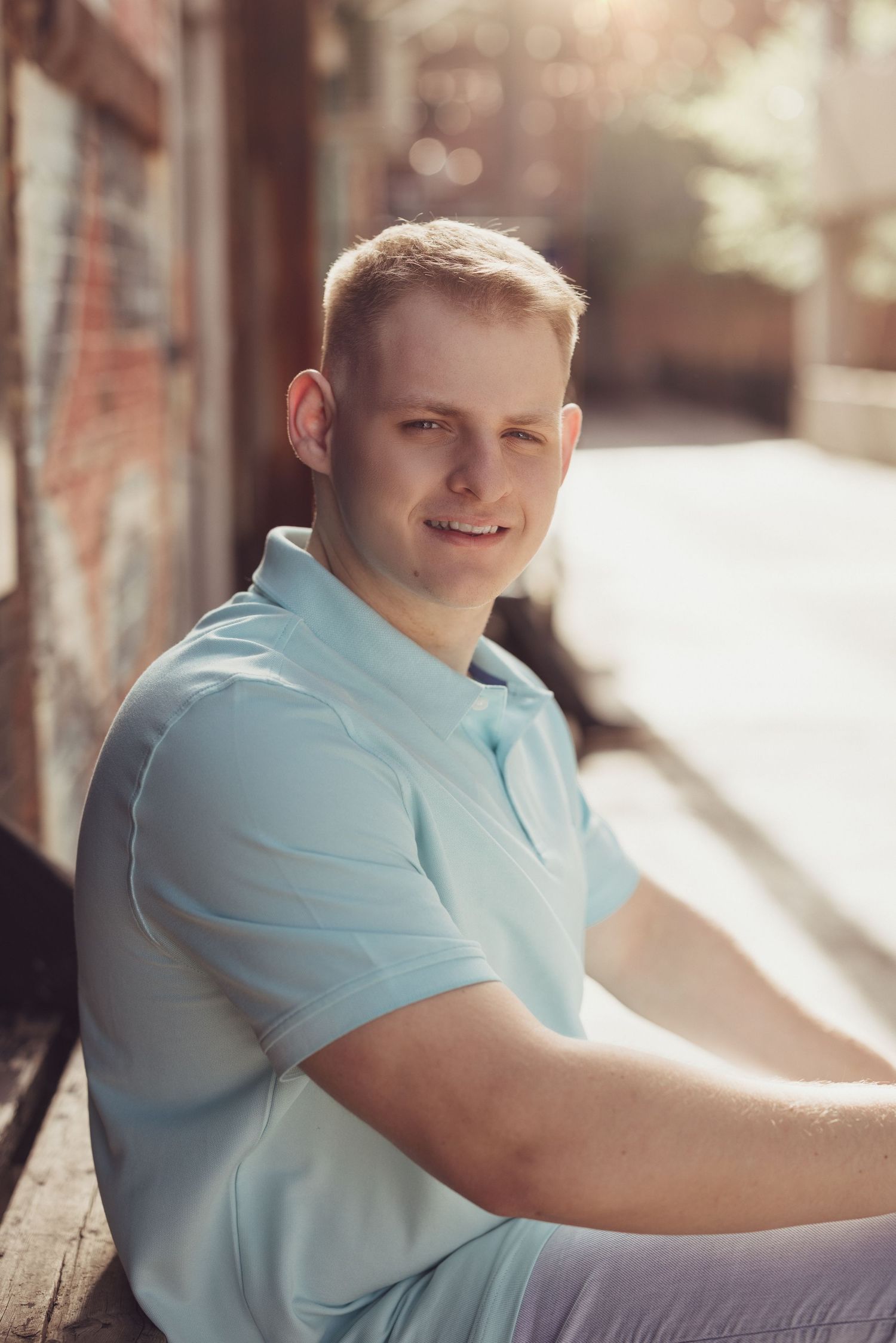 Person in light blue polo shirt relaxes outdoors in warm sunlight.