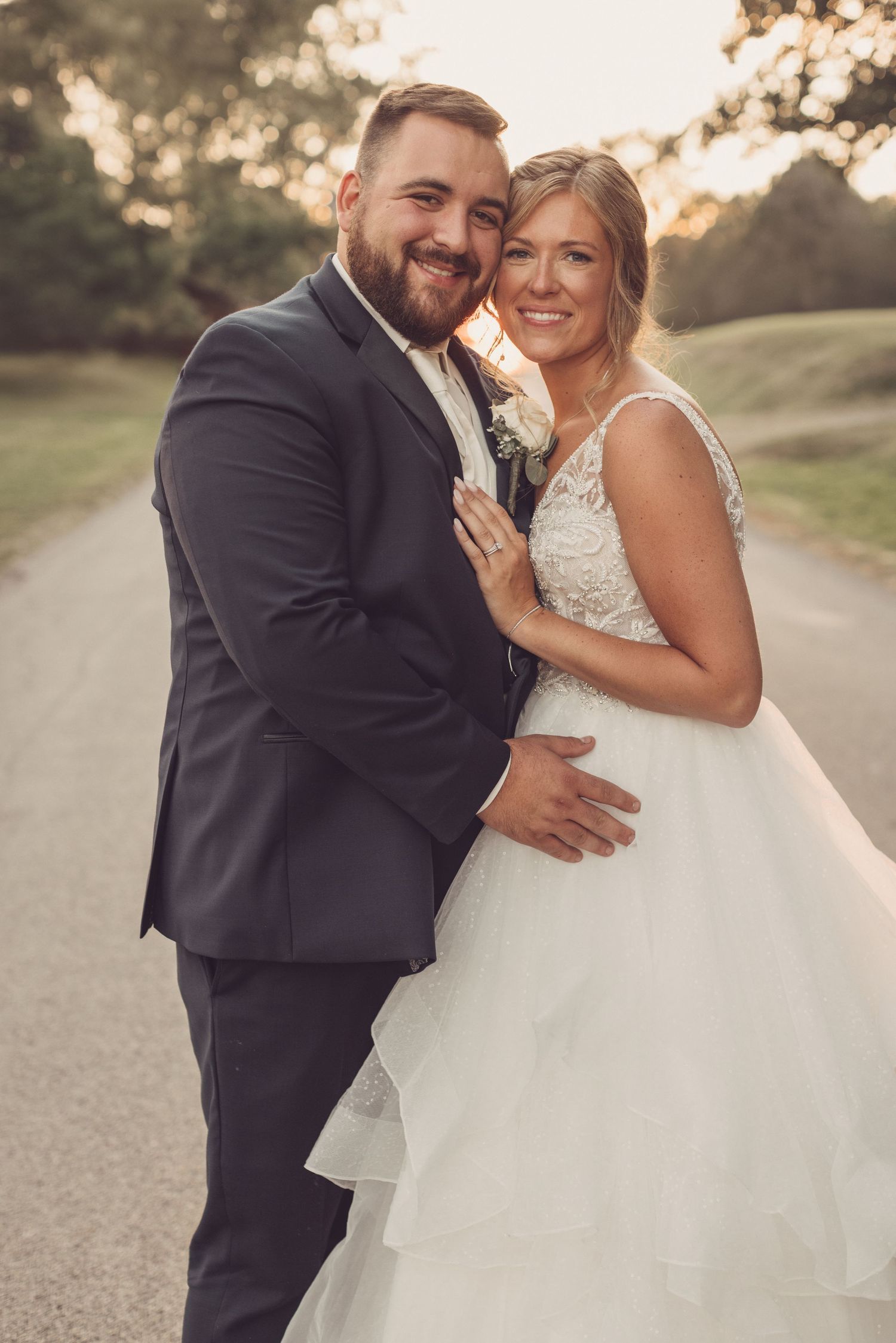 Wedding portraits showing joyful moments between newlyweds on a paved path at sunset.