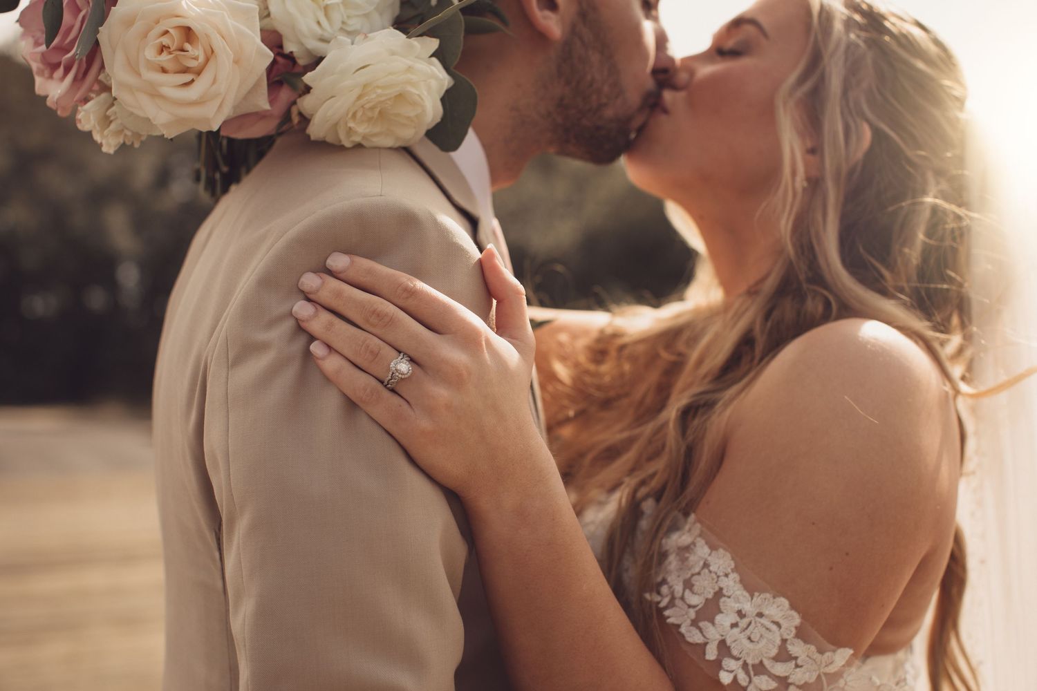 Romantic wedding couple embraces in soft sepia tones during sunset.
