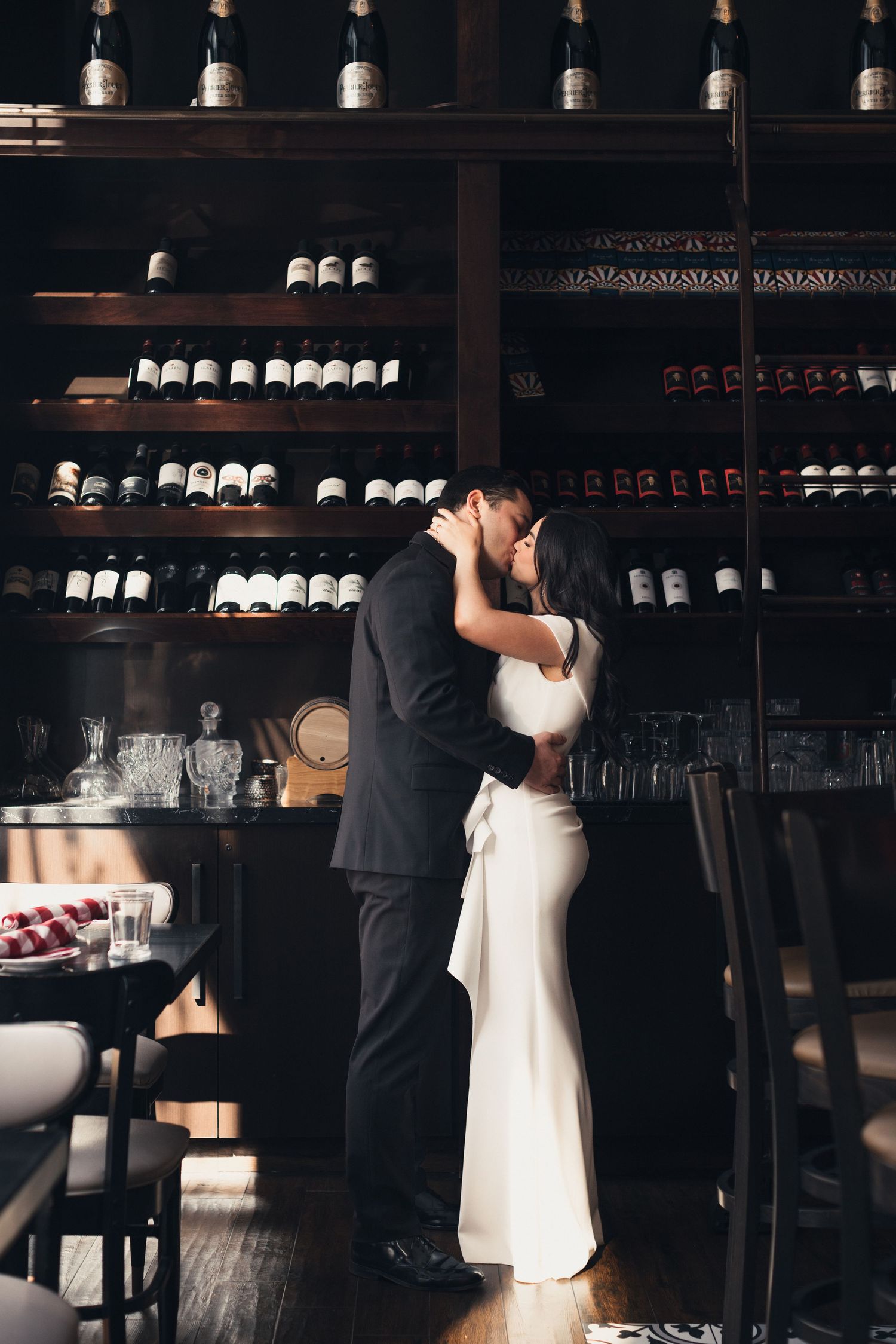 Romantic moment captured in a wine cellar with shelves of bottles creating an intimate backdrop.