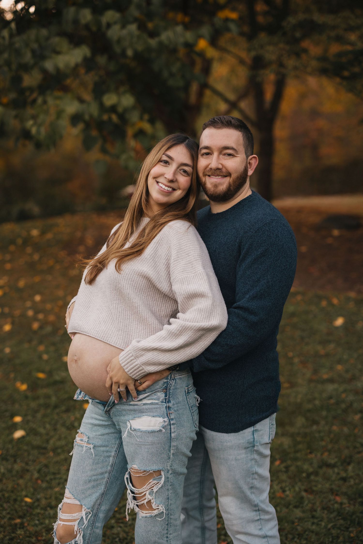 Autumn couples photoshoot with casual outfits in a park with fallen leaves.