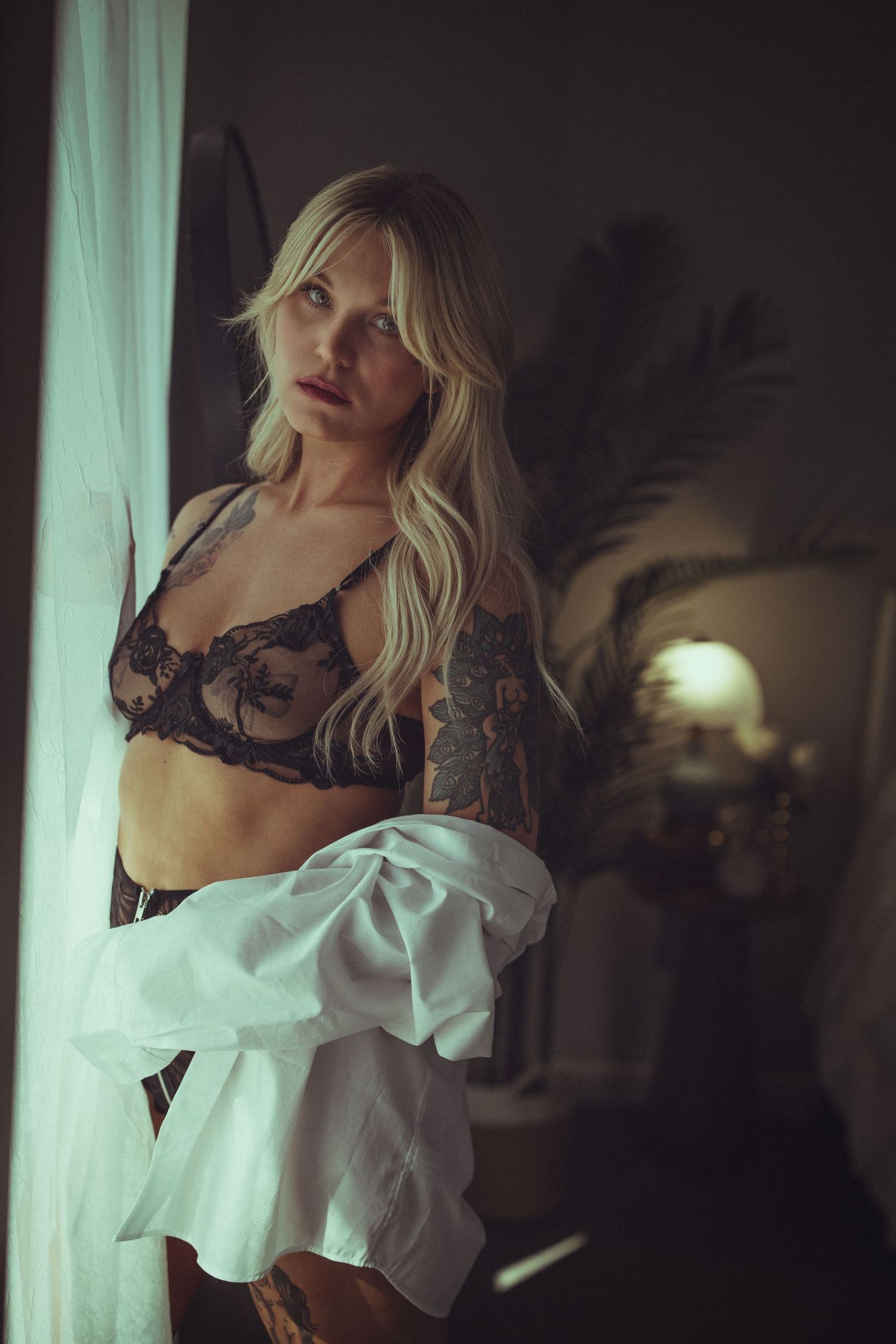 Artistic boudoir photo series featuring white shirt and black lace in moody lighting.
