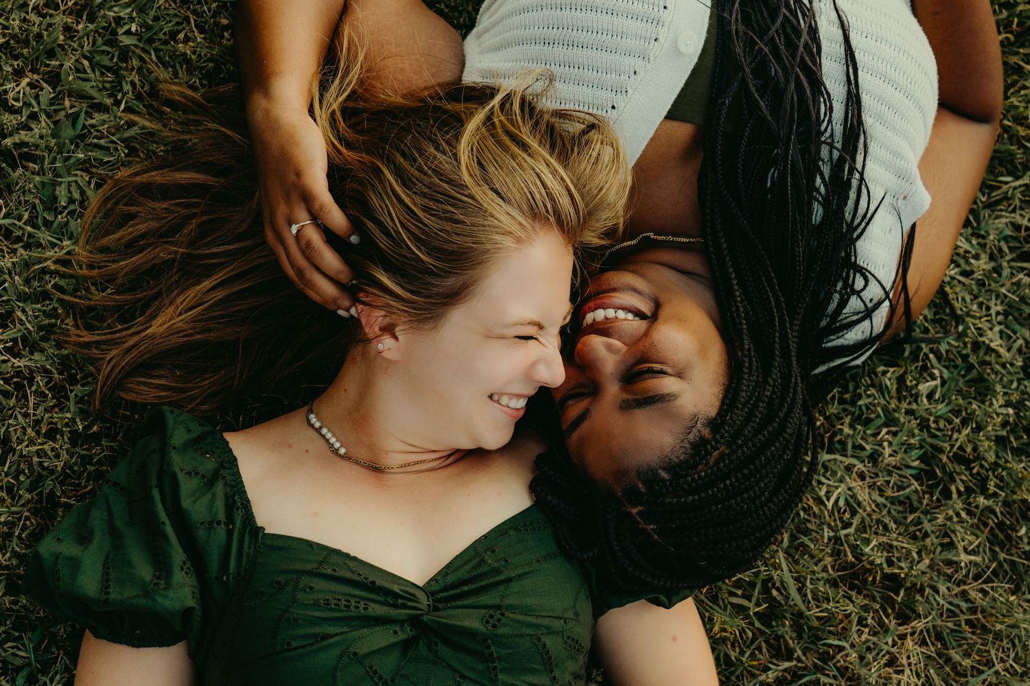 A couple lies together in the grass sharing intimate moments during an outdoor photoshoot.
