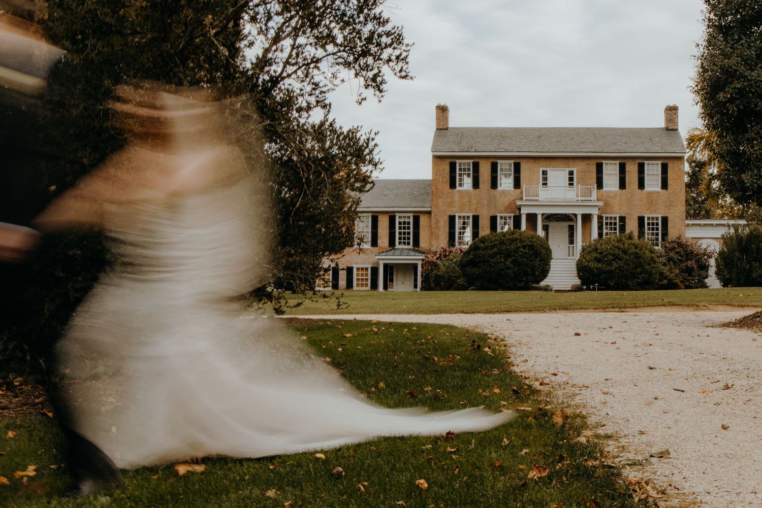 A motion blur sequence showing a ghostly white figure moving across a colonial style house exterior.