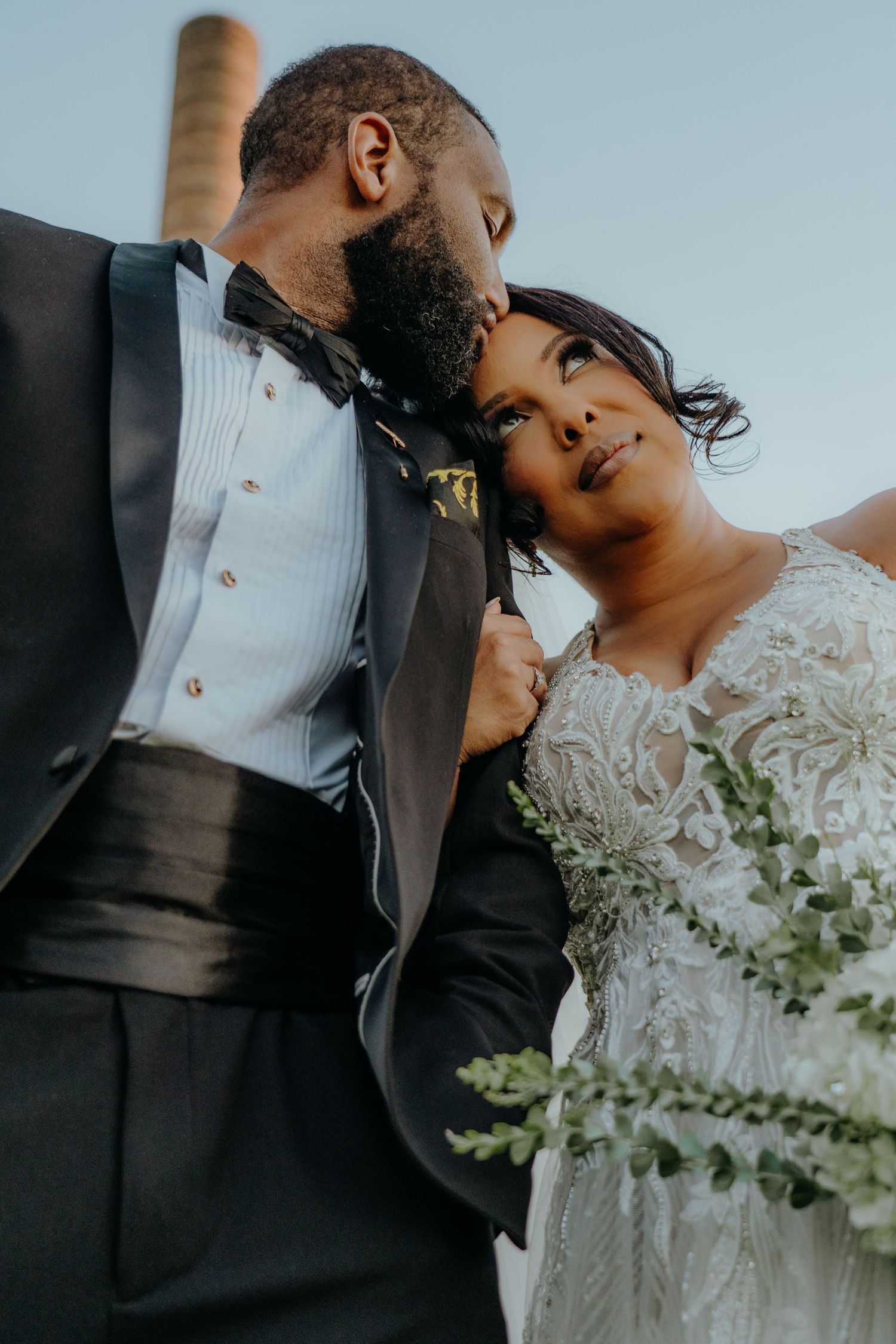 A romantic wedding photo series showing tender moments between a couple in formal attire with white flowers. Boathouse at Rocketts Landing