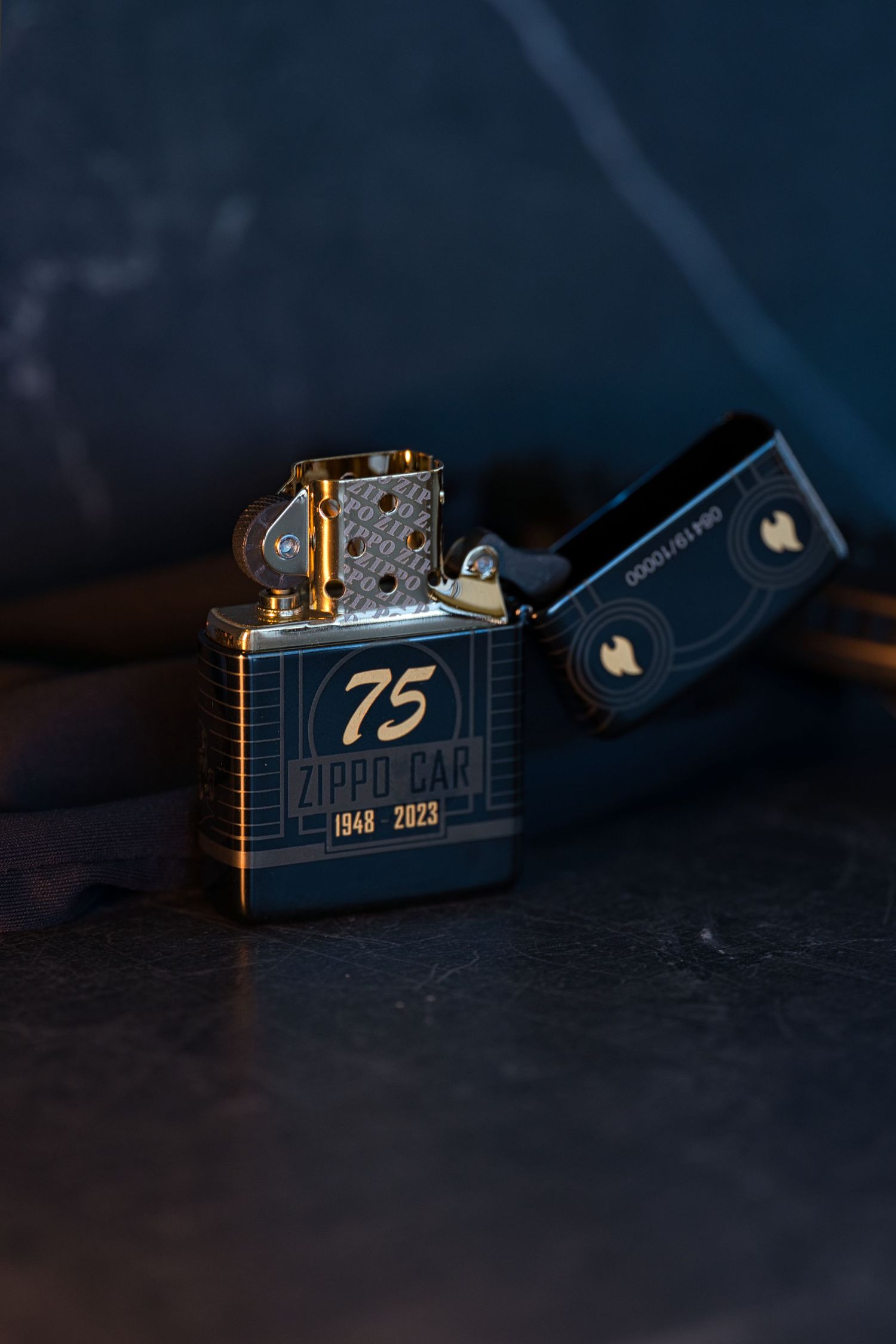 Zippo Car 75th anniversary lighter 1948-2023 edition open on dark blue surface.