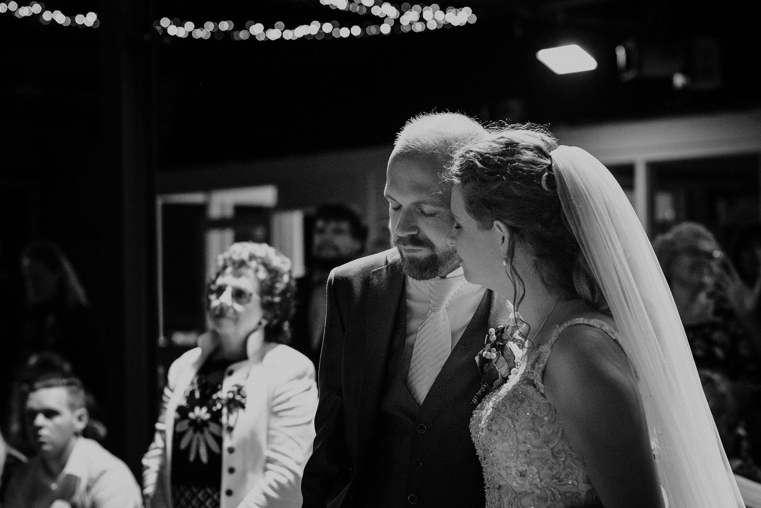 Black and white close-up of smiling bride in veil and groom sharing a tender moment at altar.Door Kim van de Broek Fotografie