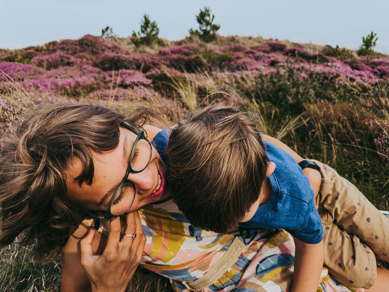 Mother and child playing and laughing together in a purple heather meadow.