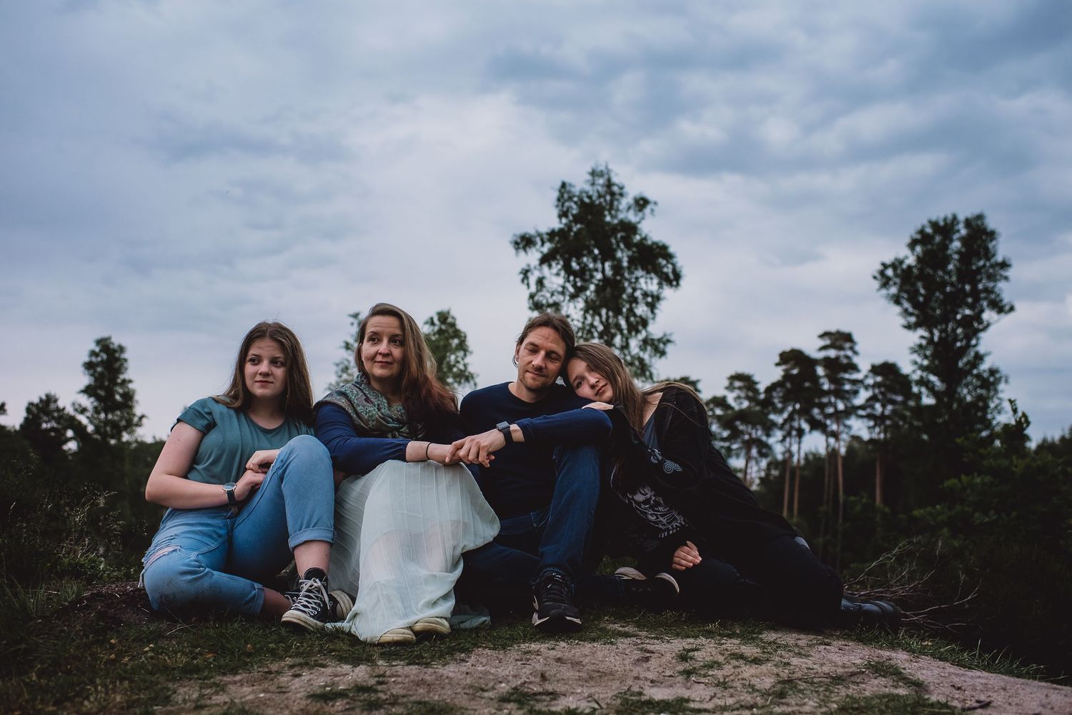 Group of four friends posing together on a rocky outcrop under cloudy skies.