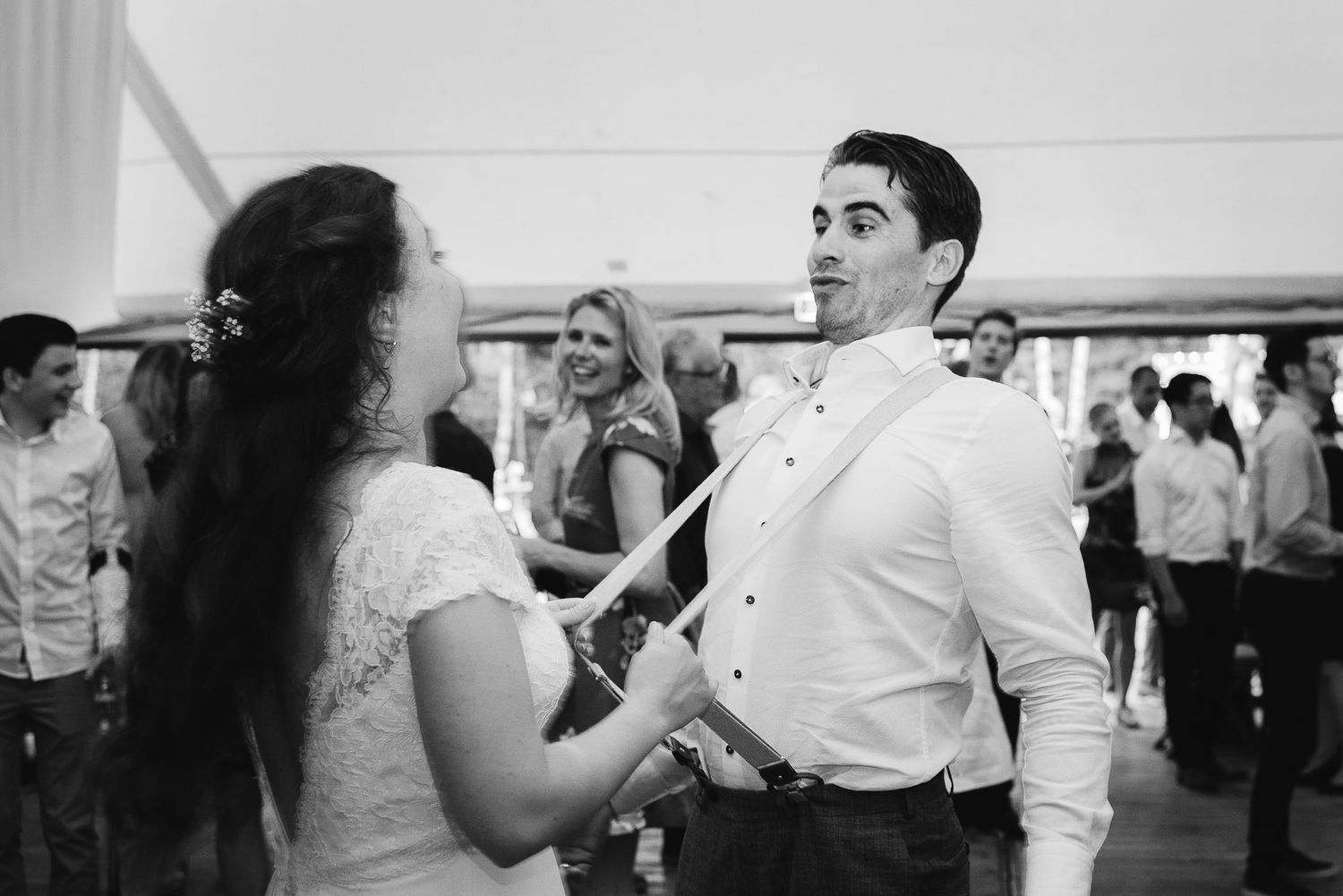 Bride and groom sharing a joyful dance moment at their wedding reception in black and white photo.