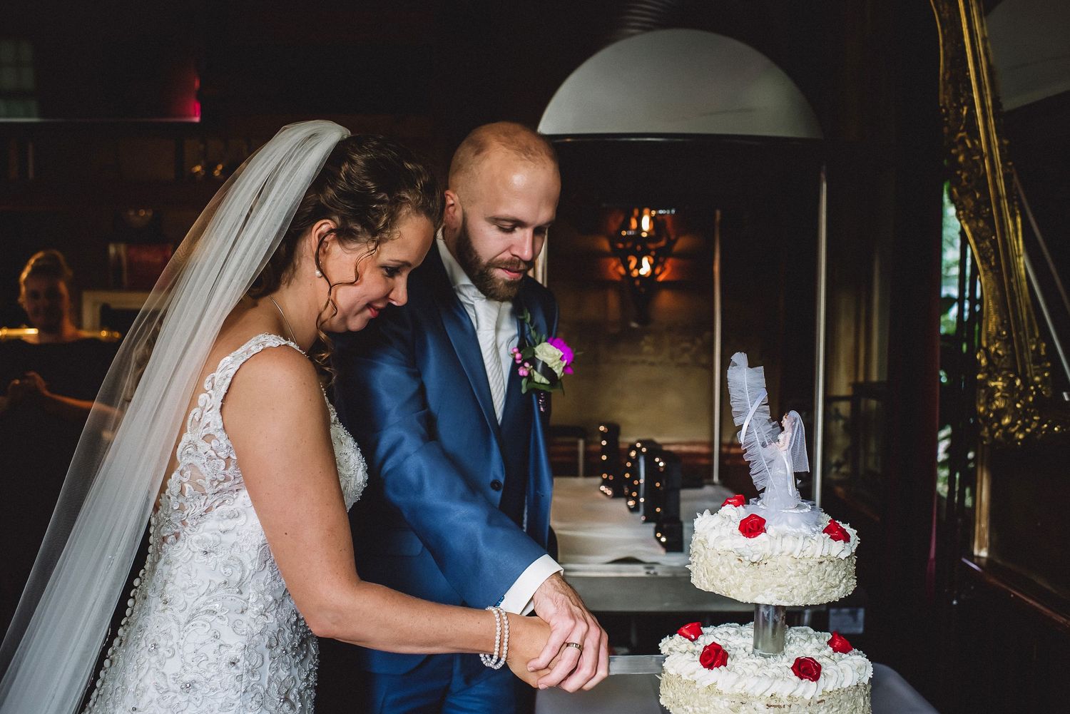 Bride and groom cut their white wedding cake together at their elegant reception.