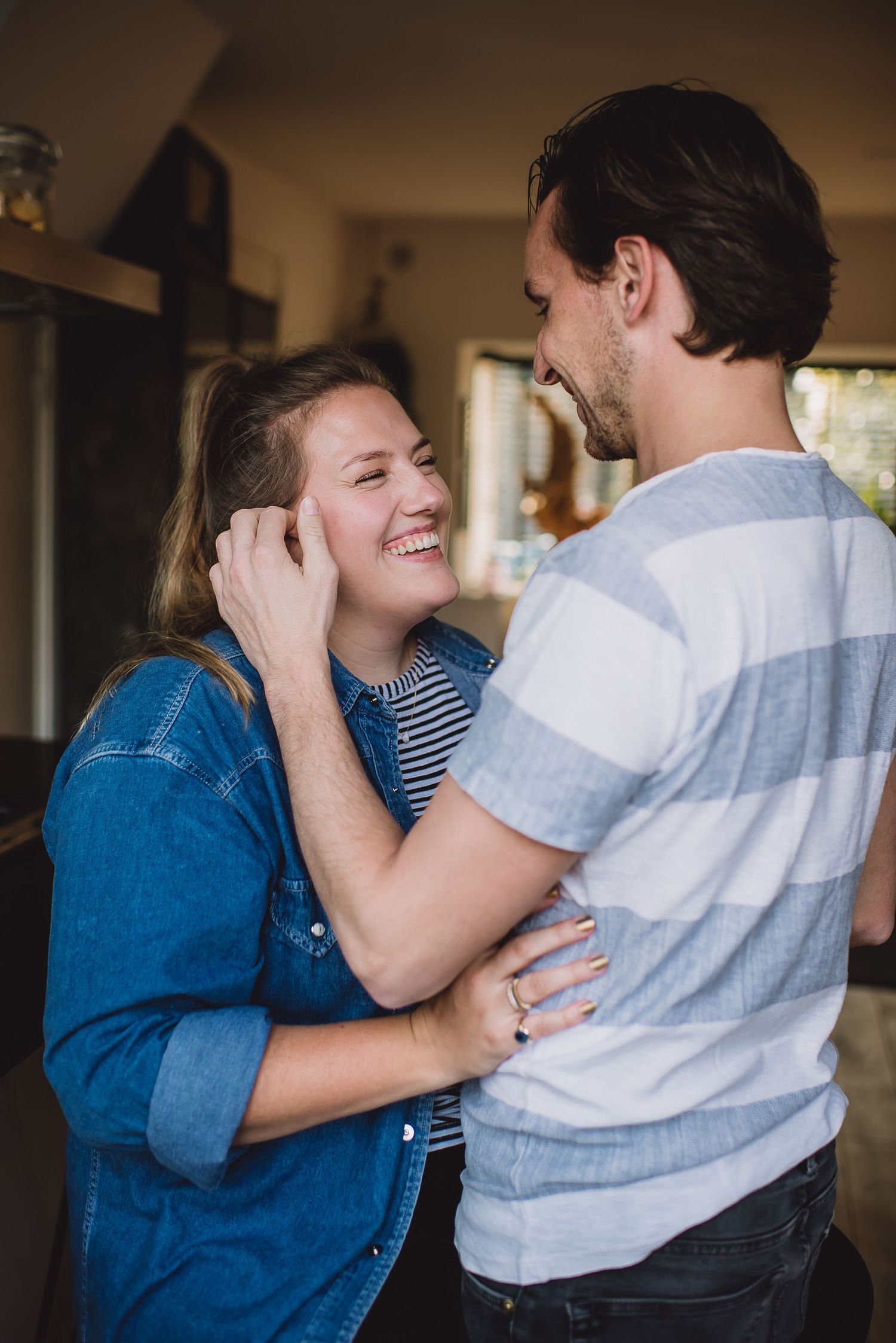 Happy couple embracing and laughing together indoors in a cozy home setting.