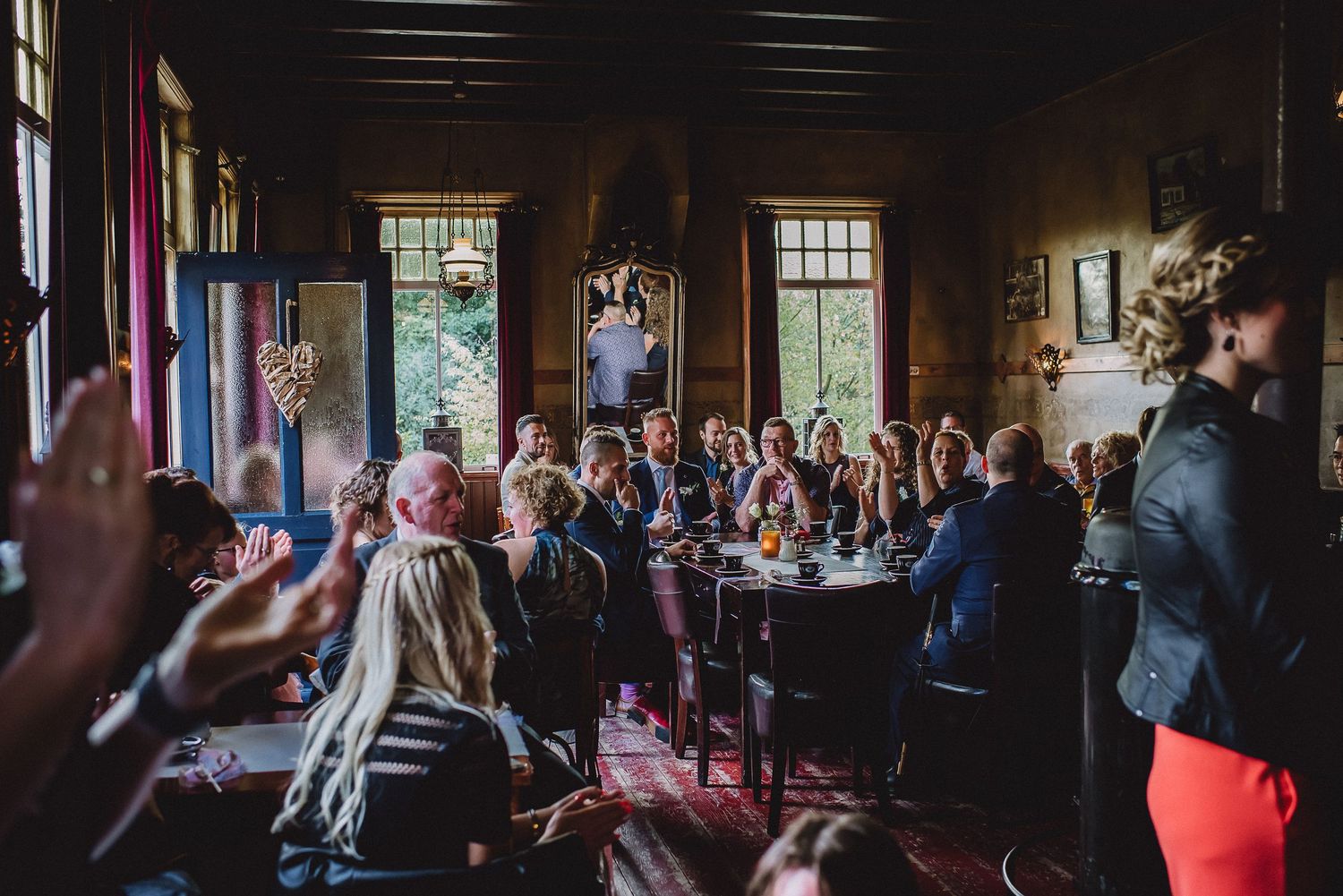 Wedding reception guests gathered around tables in a warmly lit rustic venue during celebrations.