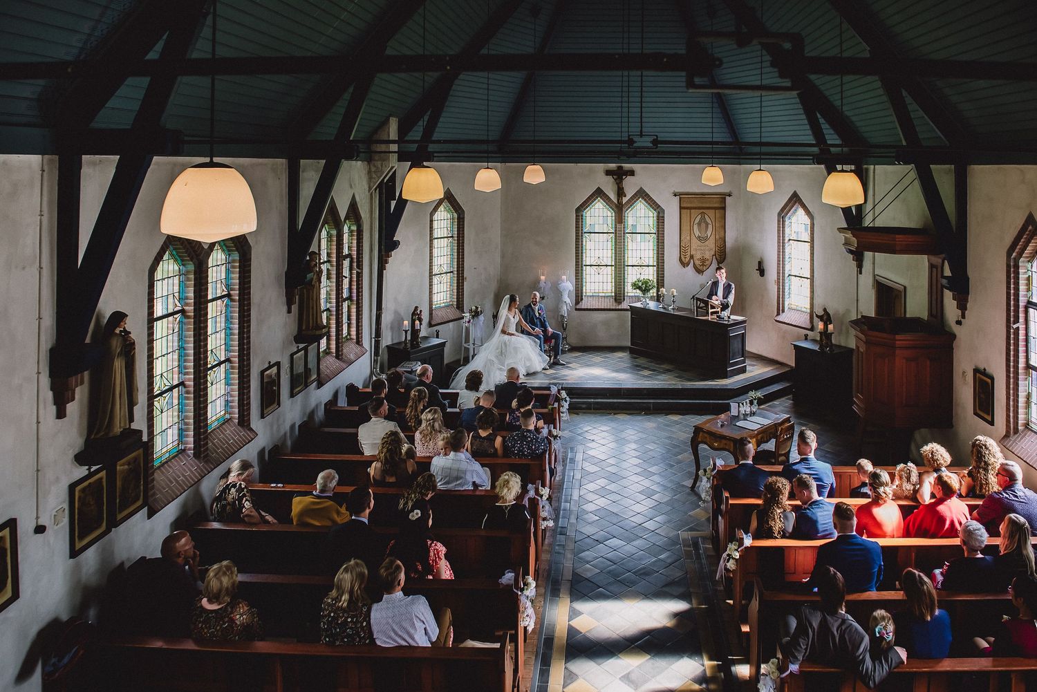 Overhead view of wedding guests seated in wooden pews during a church ceremony.