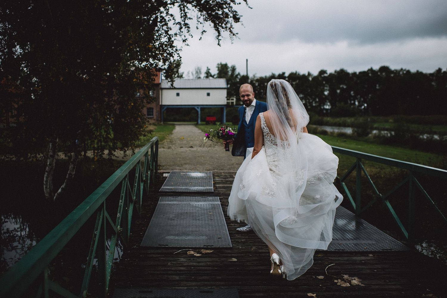 Bride in flowing white gown and veil walks toward groom gefotografeerd door documentaire trouwfotograaf Kim van den Broek