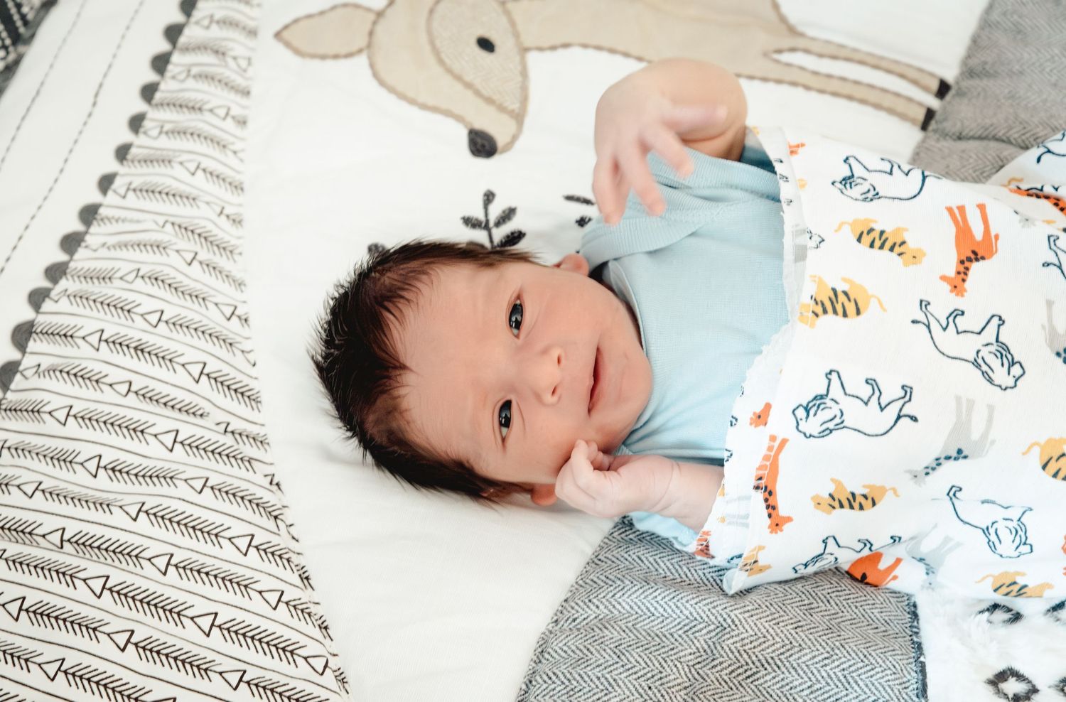 A baby boy in his crib in Ardsley, NY smile at the camera.