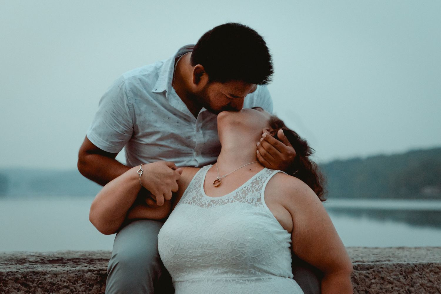 A couple shares a romantic kiss at dusk with sweeping water views during an engagement session in Westchester, NY.