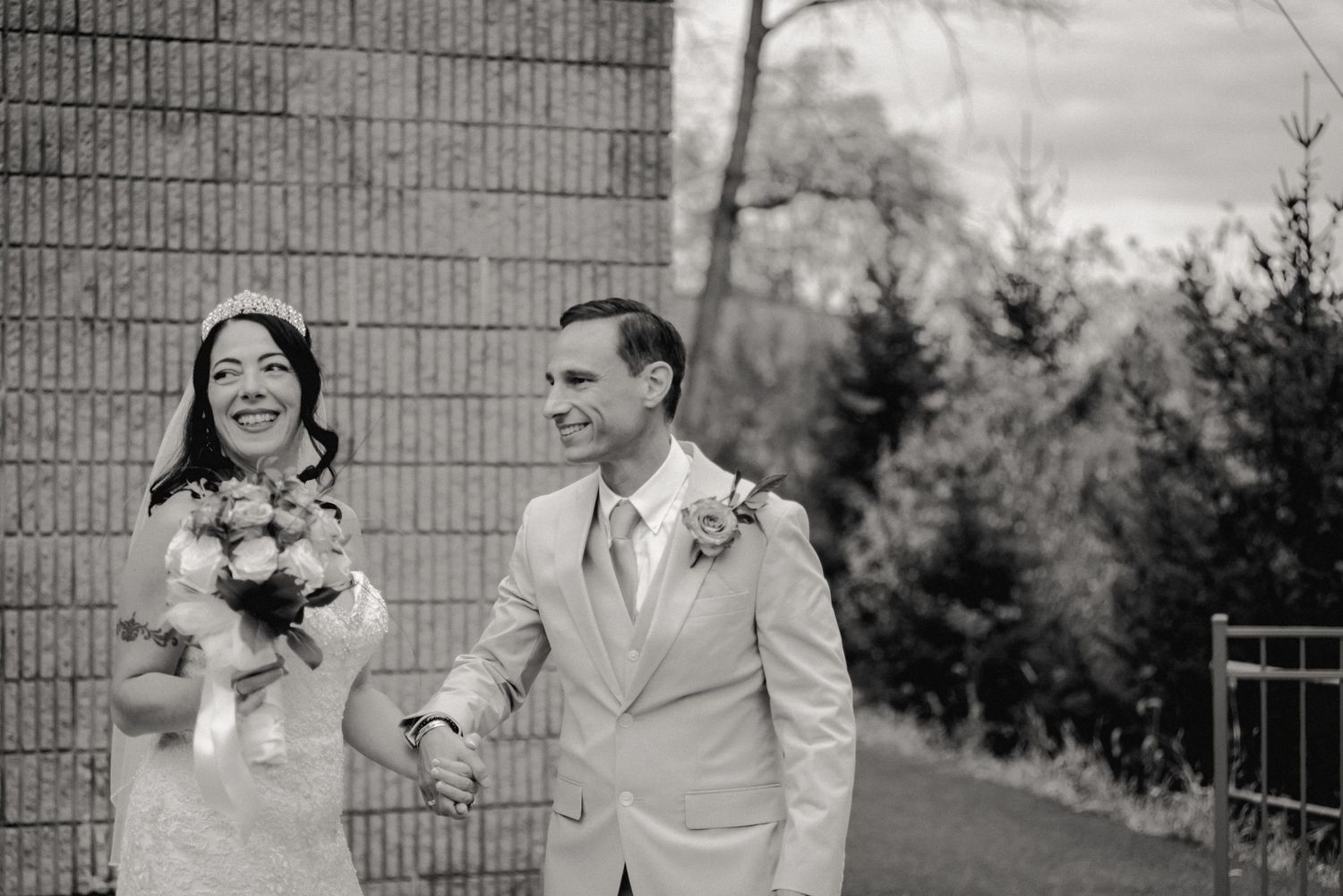 The bride and groom smile at their friends and family (not pictured) while leaving the crowd to share a quiet moment in this candid photo.